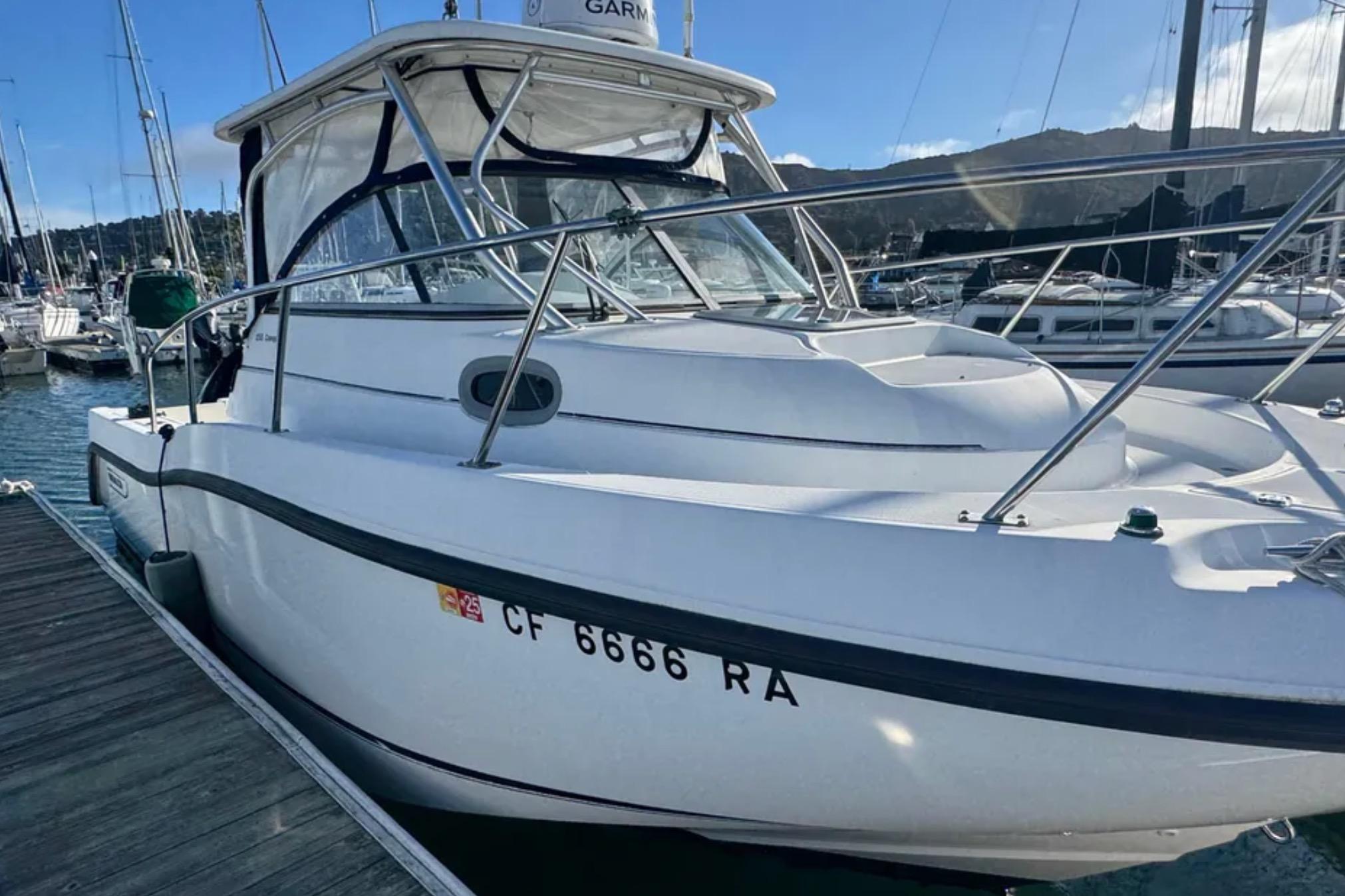 2004 Boston Whaler 255 Conquest boat docked at marina, clear sky background.