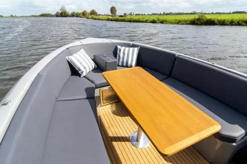 Luxurious Rand PLAY 24 boat interior with wooden table and cushioned seating, 2022 model.