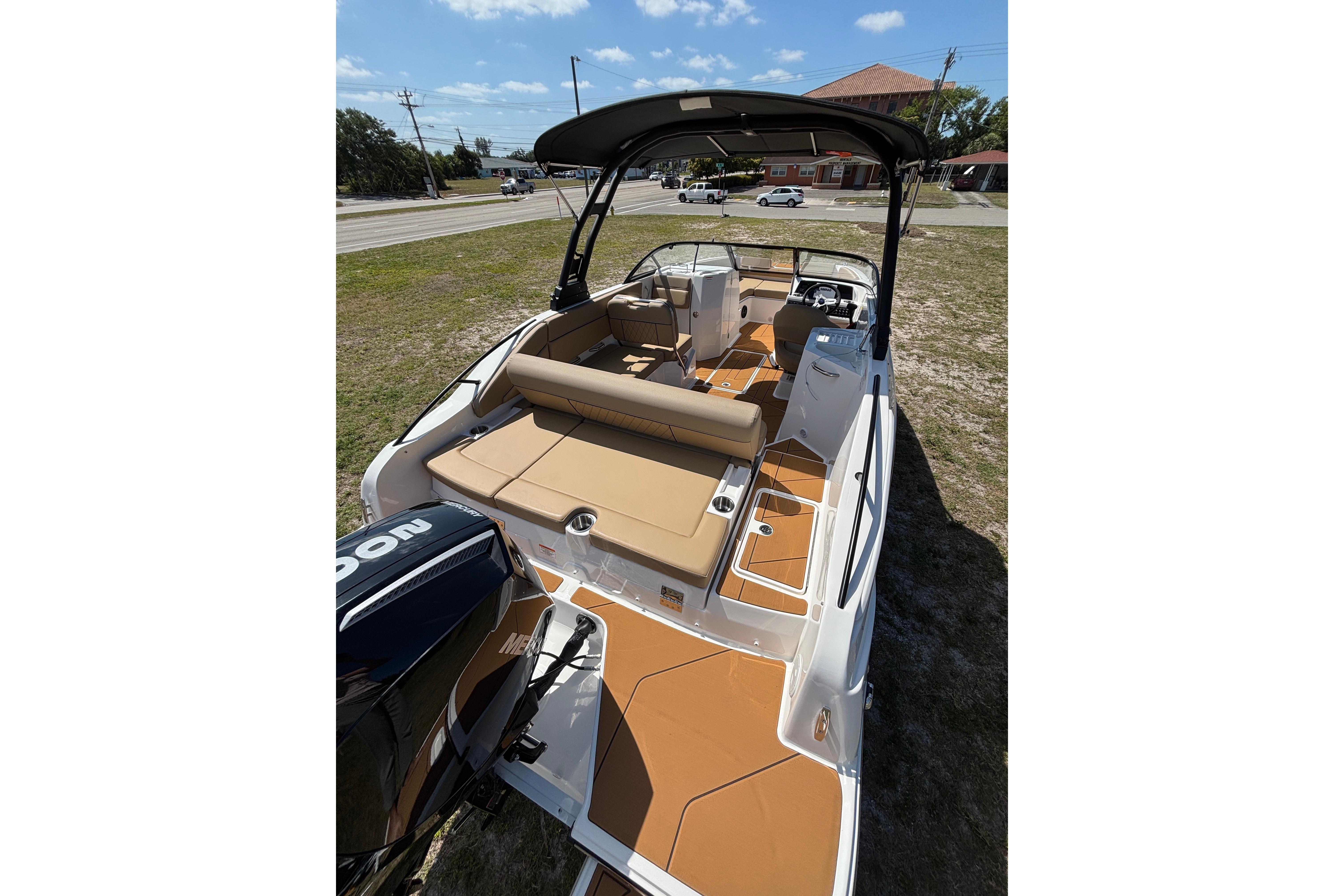 2026 Bayliner D22 boat with tan seating and black canopy, parked on grass.