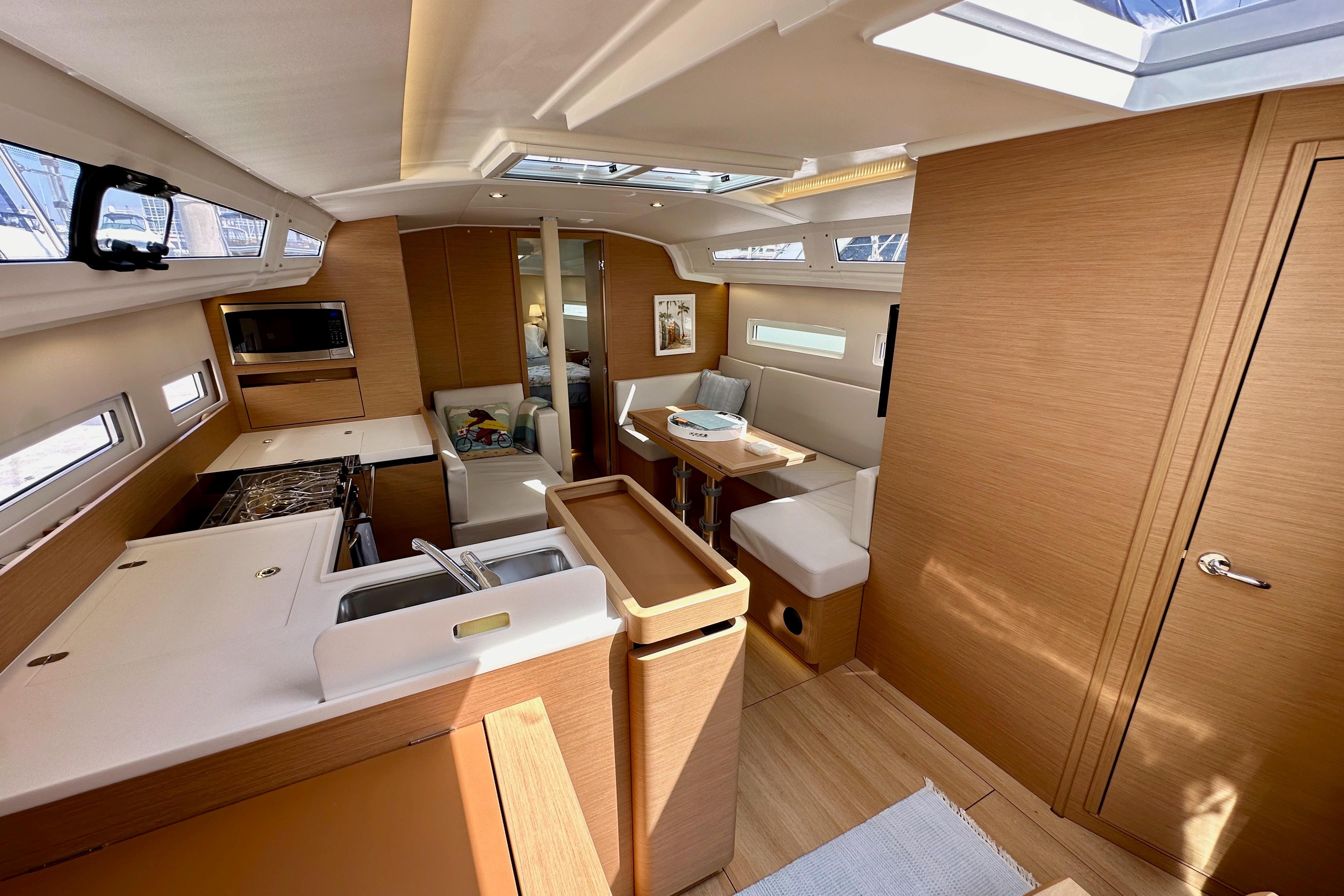 Interior of 2024 Jeanneau Sun Odyssey 410 yacht, featuring modern kitchen and seating area.