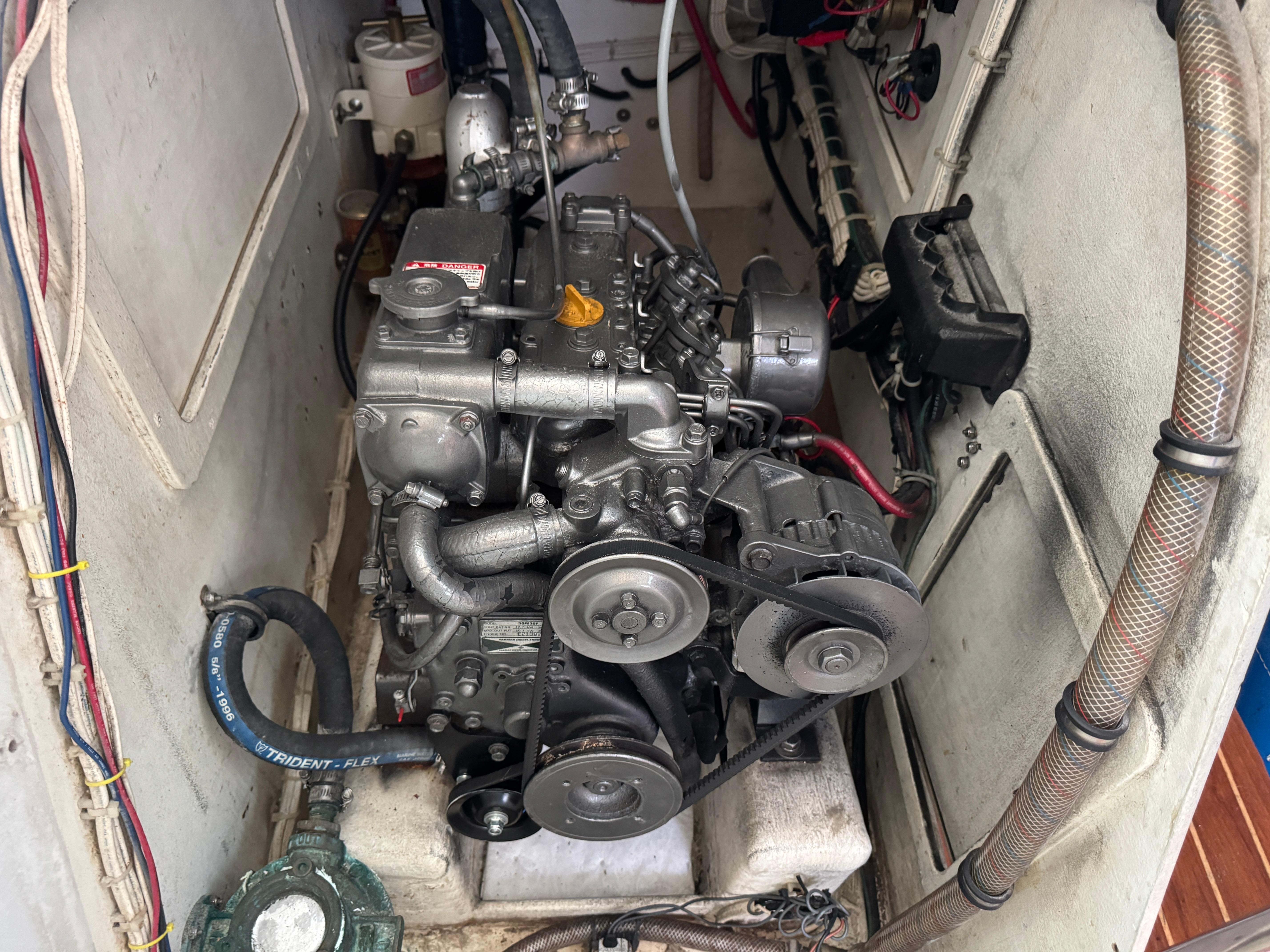 Engine compartment of a 2000 Wyliecat 48 sailboat, showcasing mechanical components and belts.