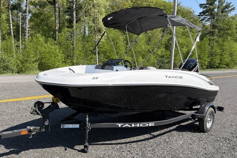 2026 Tahoe T16 boat on trailer, parked on road with lush green forest background.