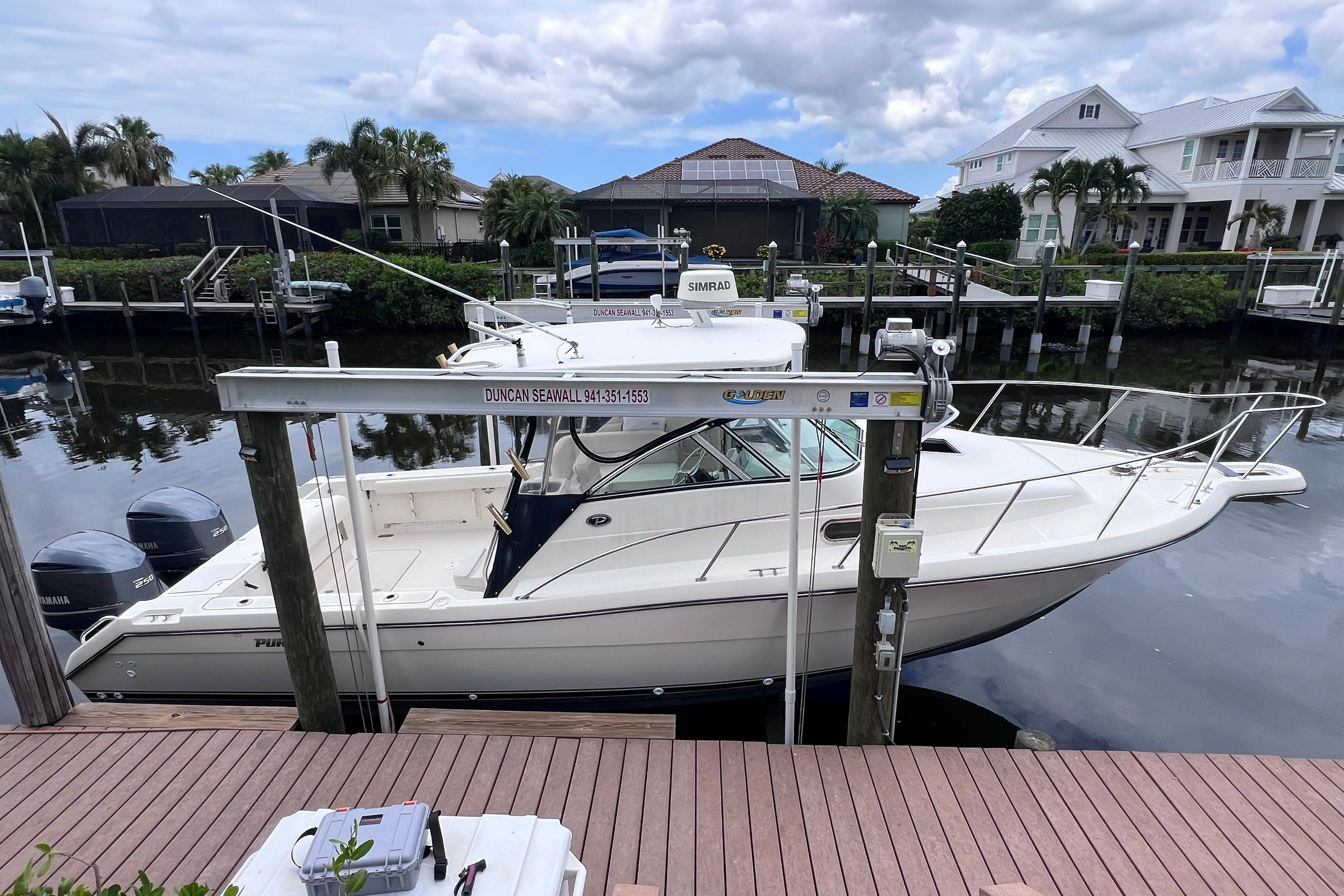 2005 Pursuit 3070 Offshore boat docked at a marina with scenic waterfront homes.