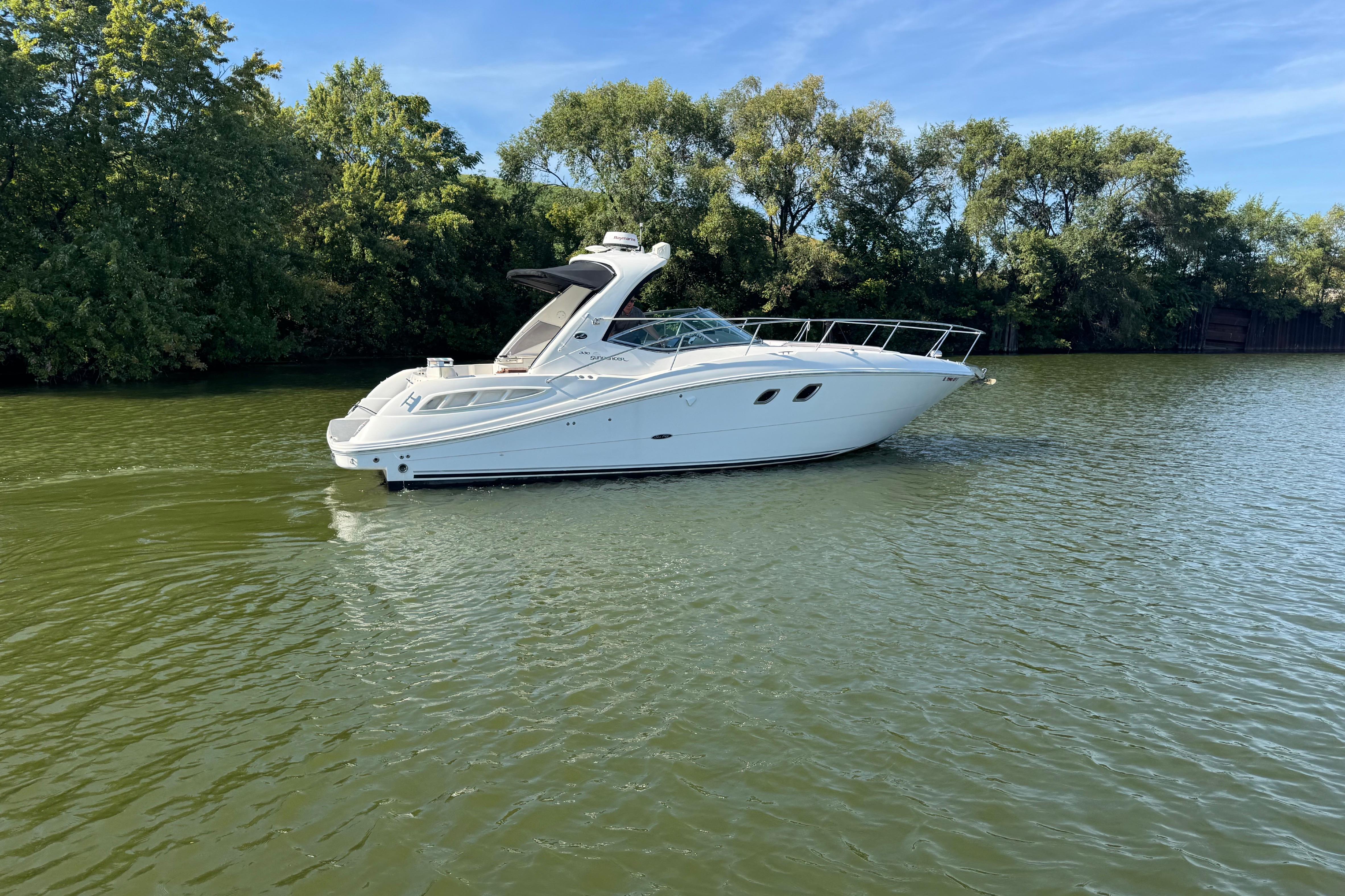 2008 Sea Ray 350 Sundancer yacht cruising on a serene lake with lush greenery.