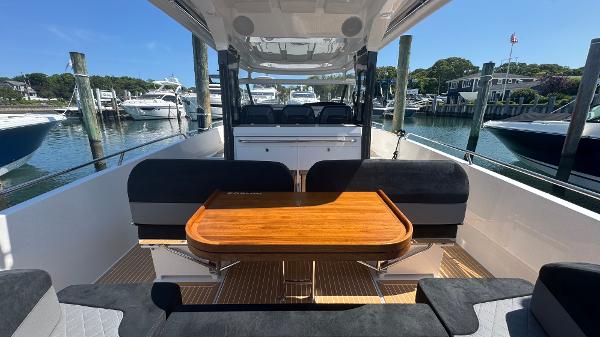Nimbus T11 2025 boat interior with wooden table, black seating, docked at marina.
