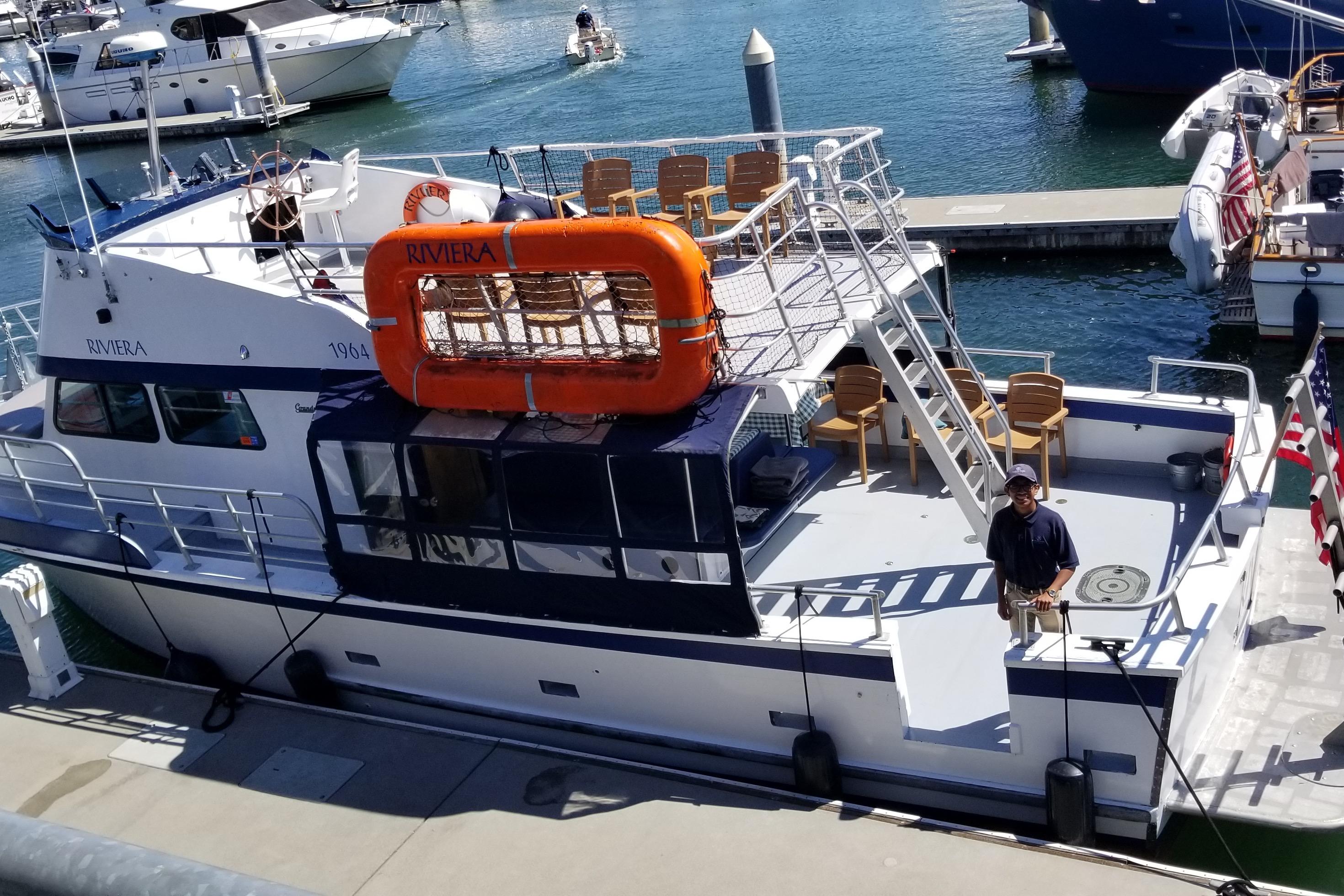 1964 Grandy Tour Boat docked, featuring upper deck seating and lifeboat, with a person standing on deck.