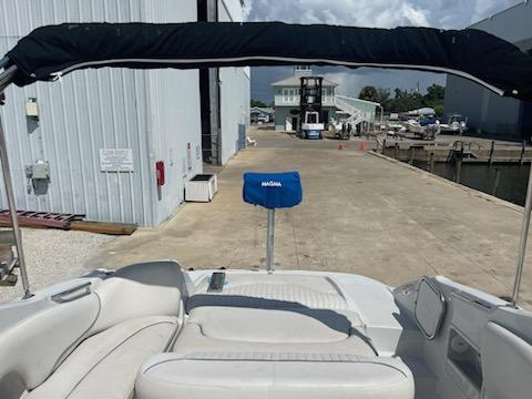 2005 Crownline 275 CCR boat with canopy, docked near a marina building.
