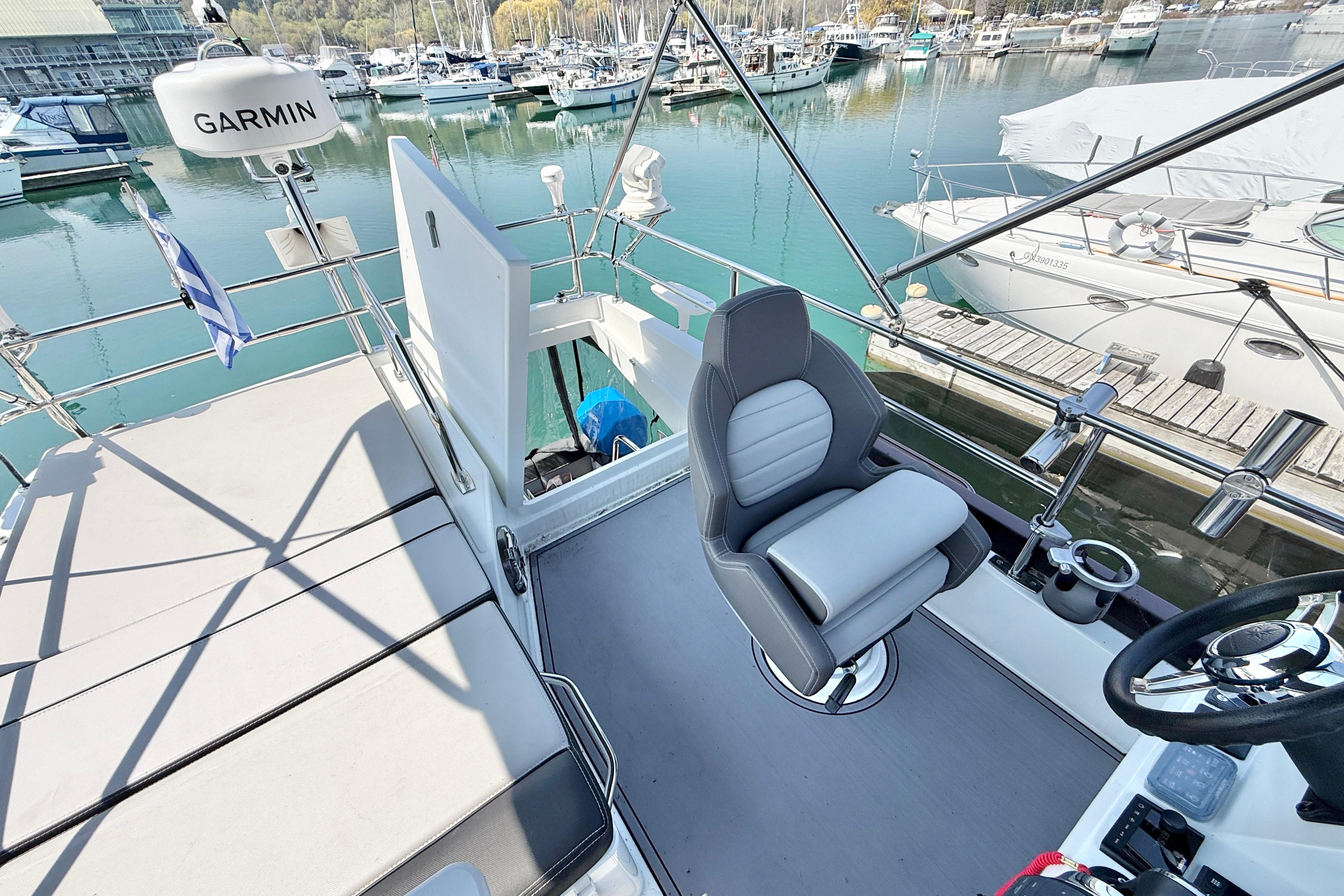 Flybridge of 2022 Jeanneau NC 1095 Fly yacht with helm and seating, docked at marina.