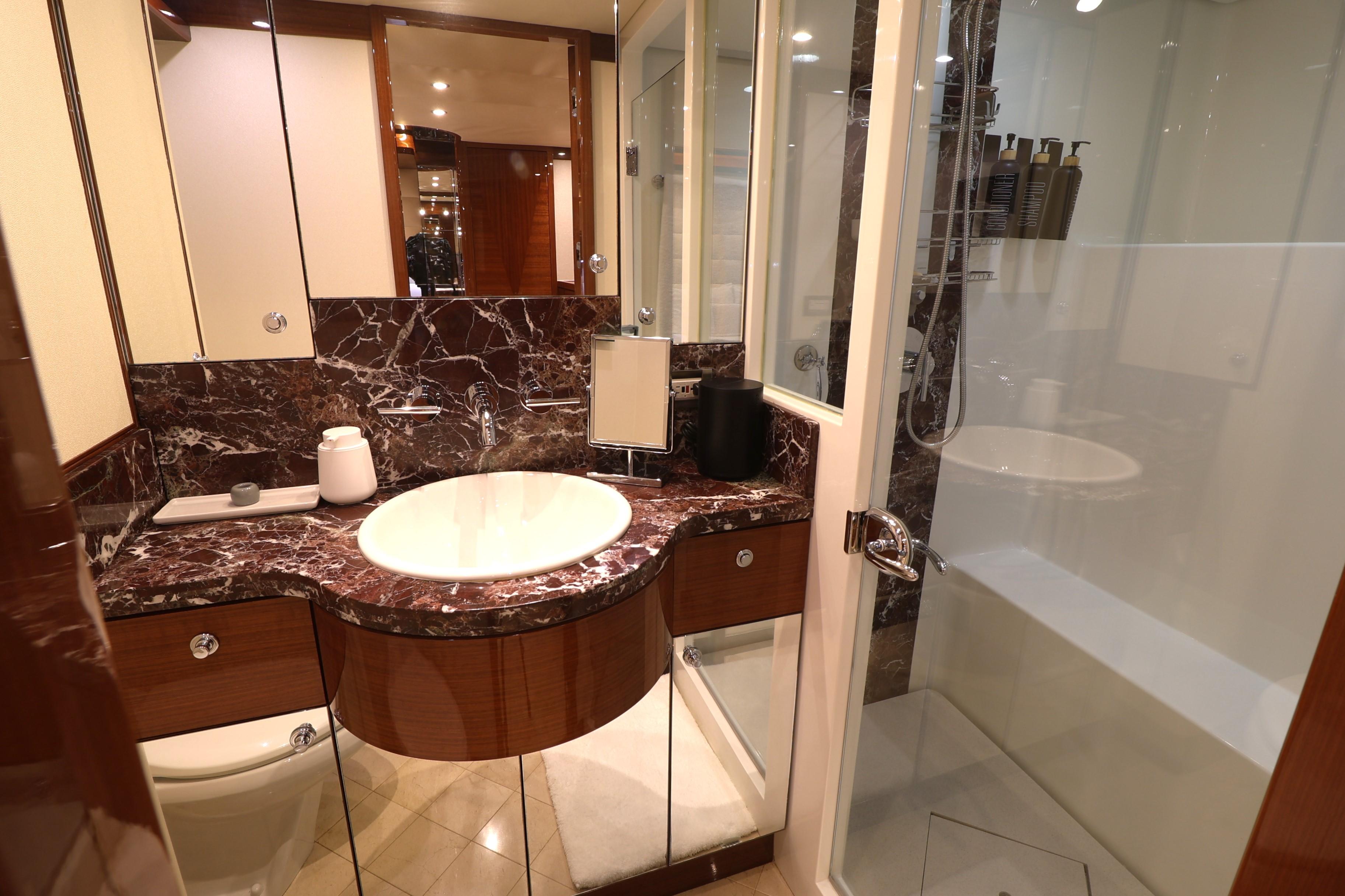 Luxurious bathroom in 2013 Cheoy Lee Bravo yacht with marble countertop and glass shower.