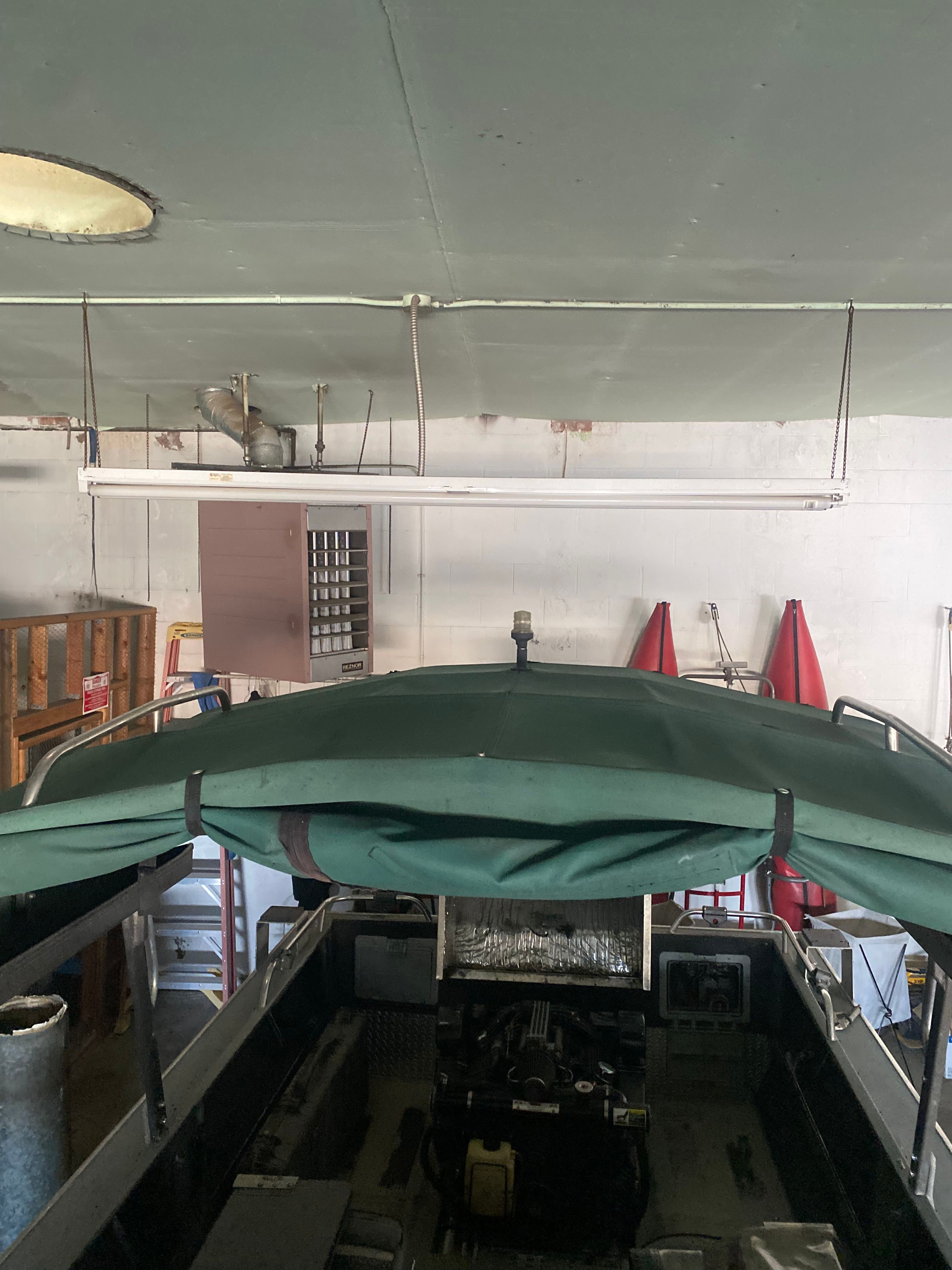 1993 Jetcraft Fastwater boat in a garage with green cover.