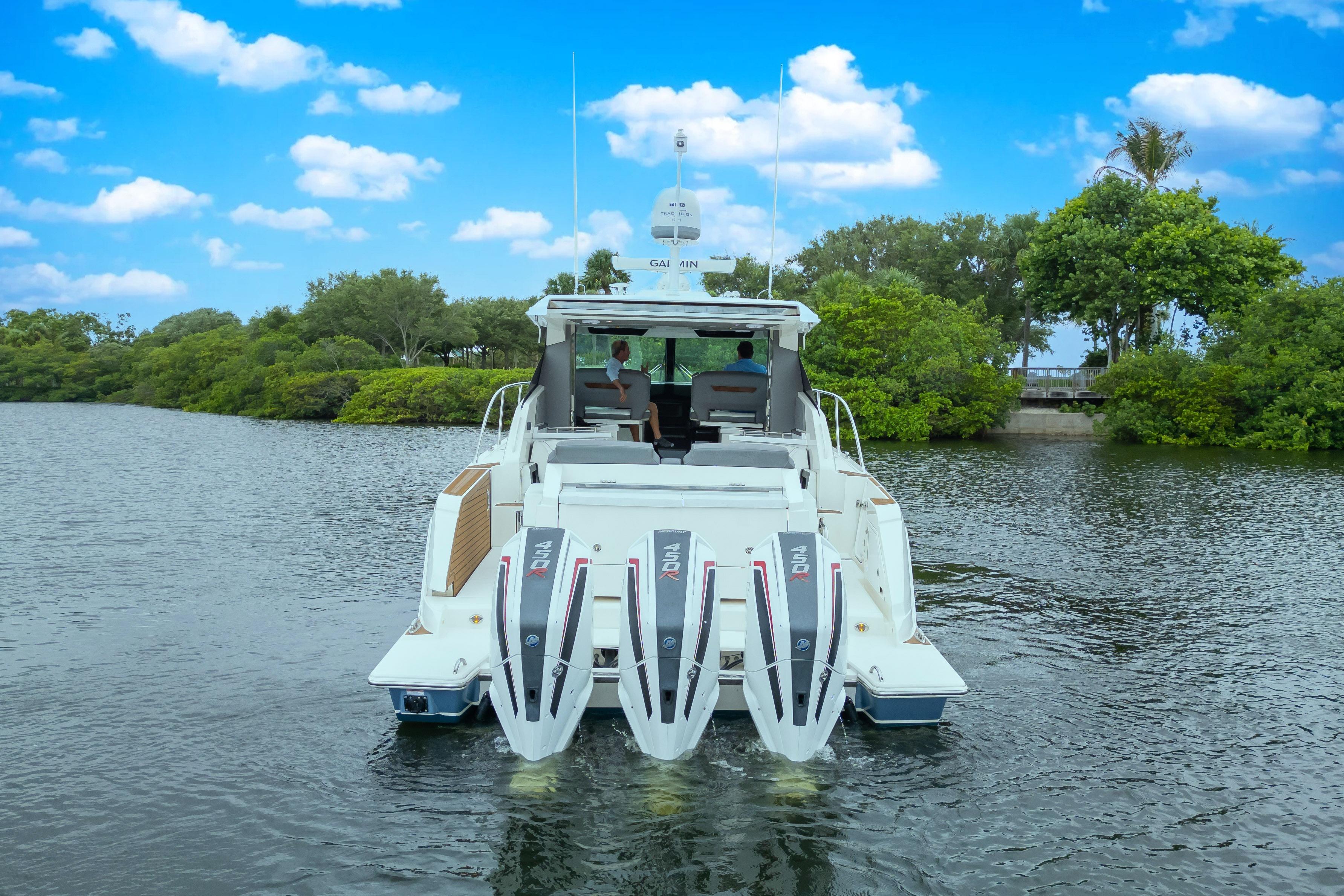 2021 Tiara Sport 43 LE boat cruising on a scenic river under a blue sky.