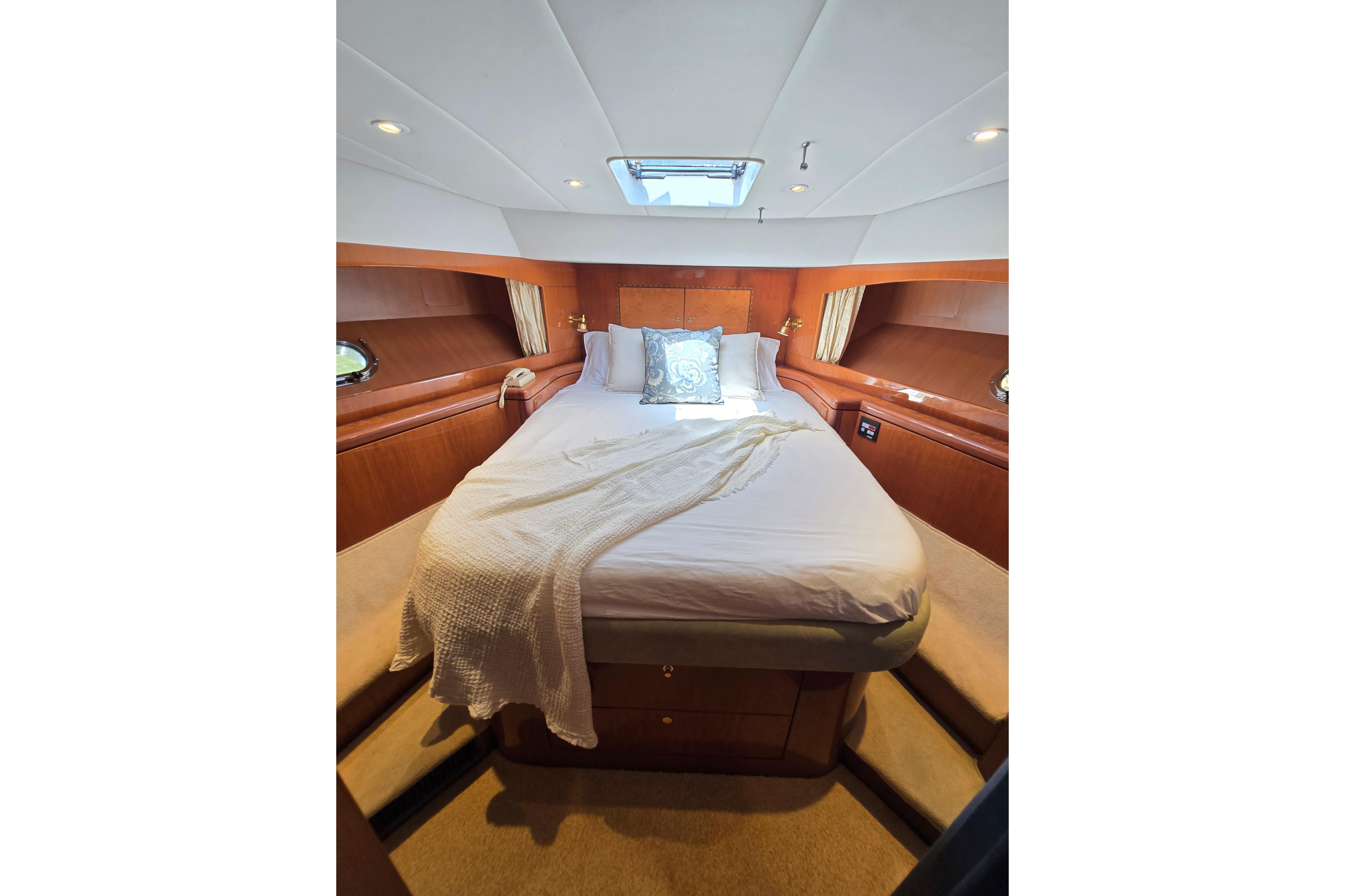 Luxurious bedroom interior of 2004 Grand Harbour 58 yacht with cozy bedding and elegant wood finish.