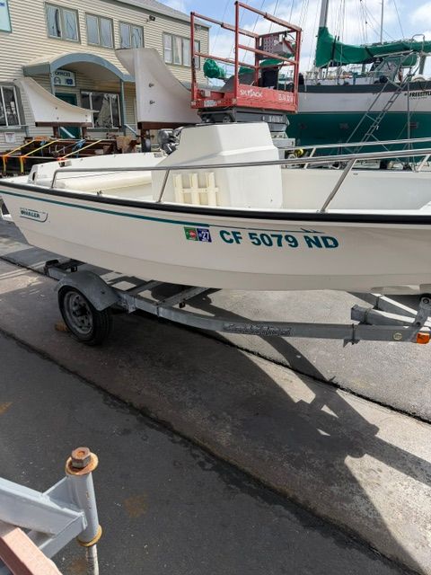 A white Boston Whaler jet boat on a trailer, parked on a concrete surface.