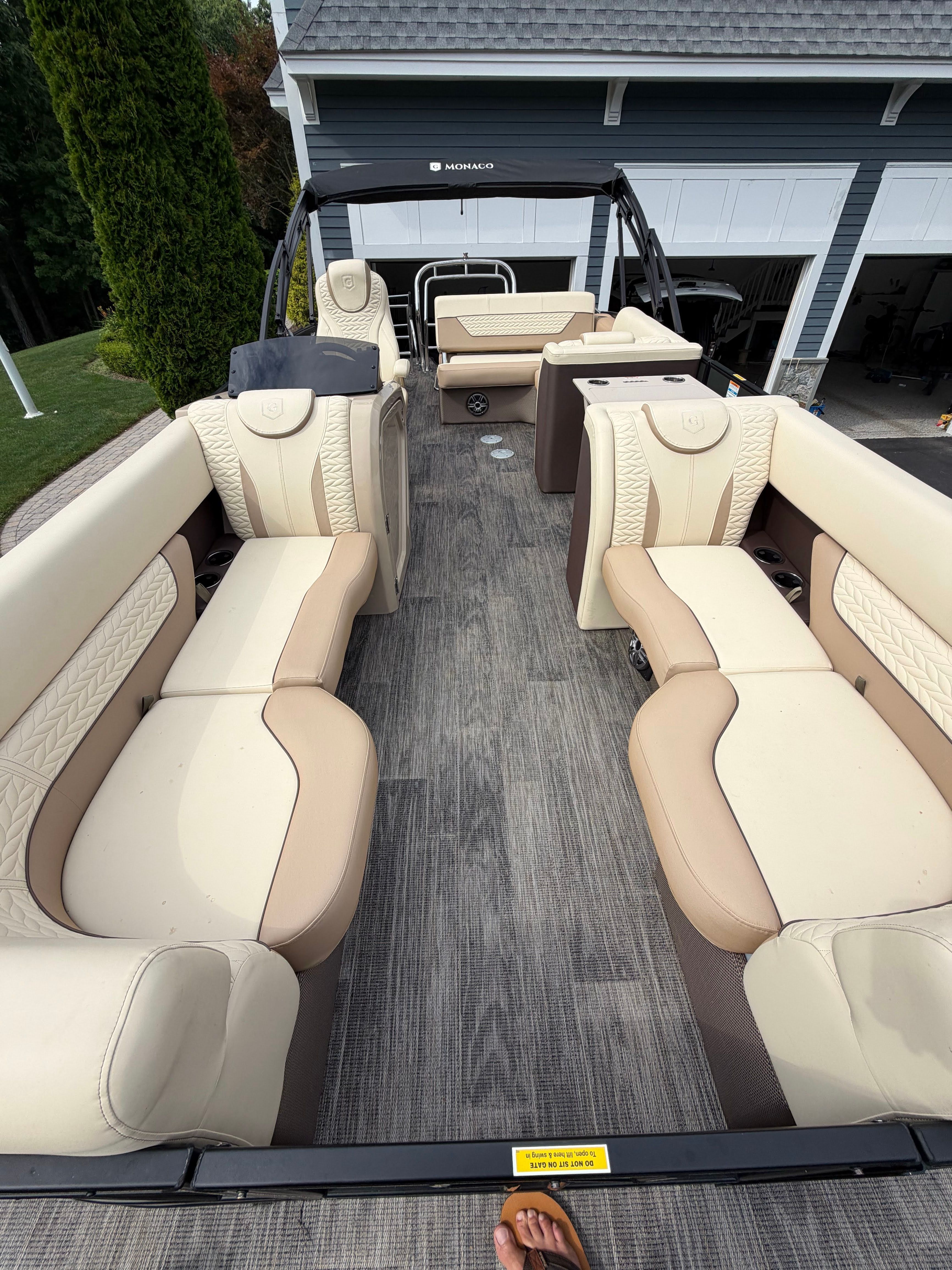 The image shows the interior of a 2025 Godfrey Monaco Cruise pontoon boat with elegant seating.