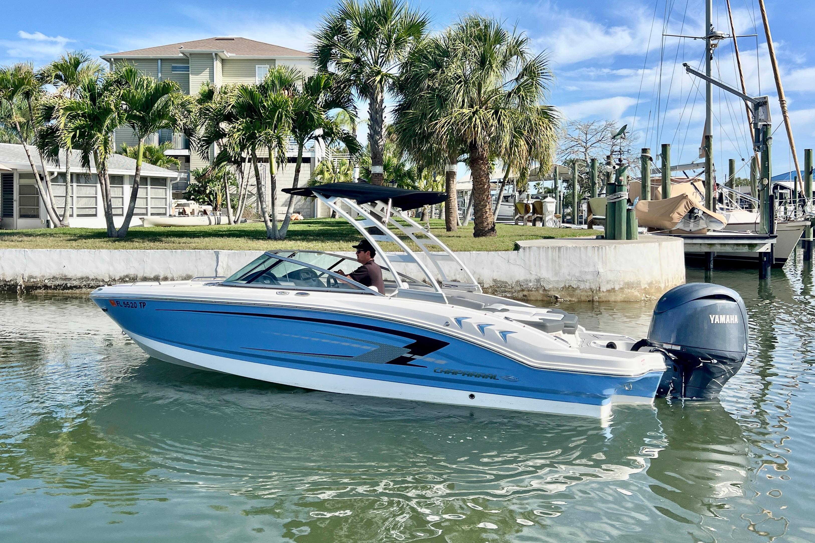 2023 Chaparral 21 SSi OB boat on water, with palm trees and houses in background.