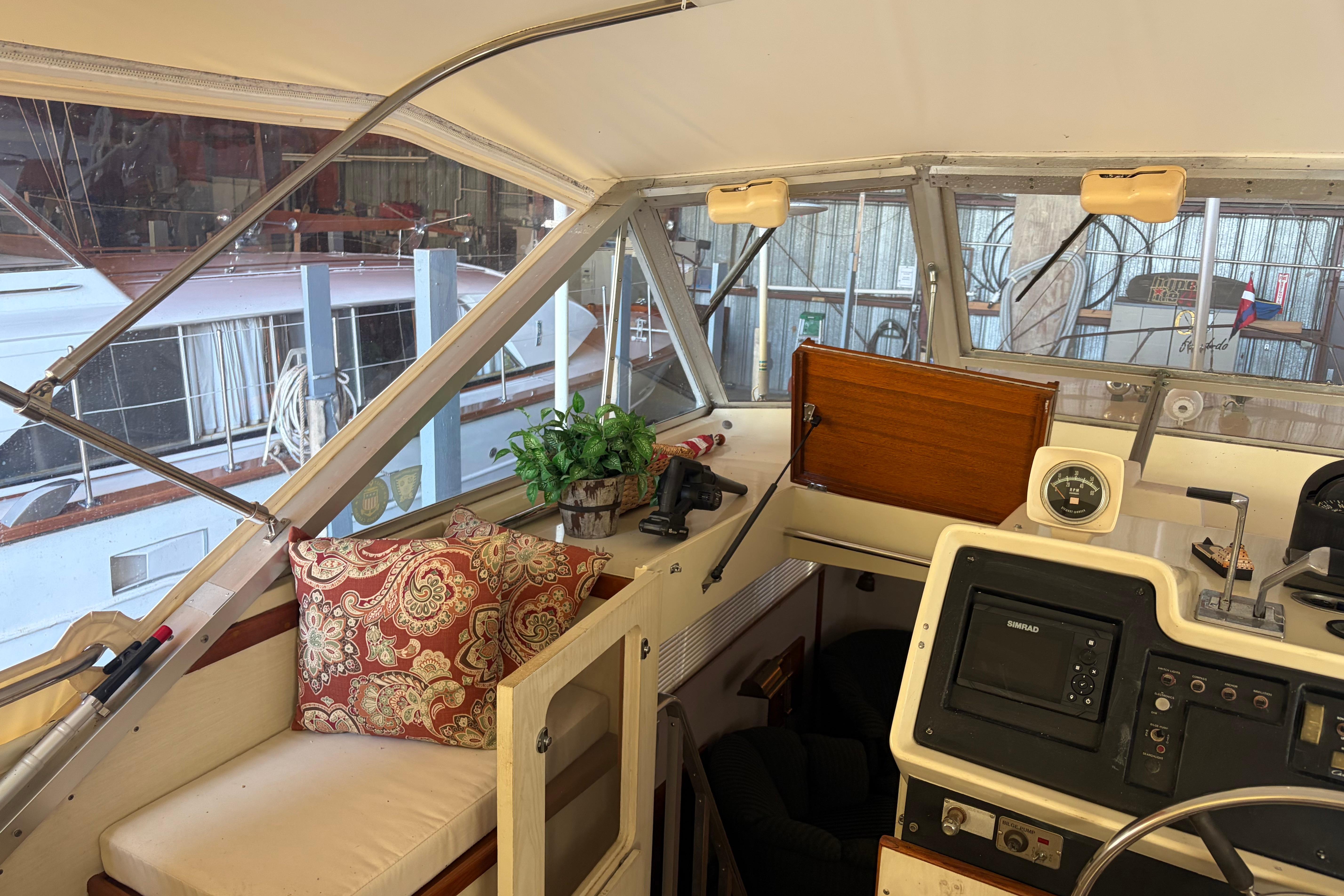 Interior of 1971 Chris-Craft 42 Commander boat with helm, seating, and decorative pillows.