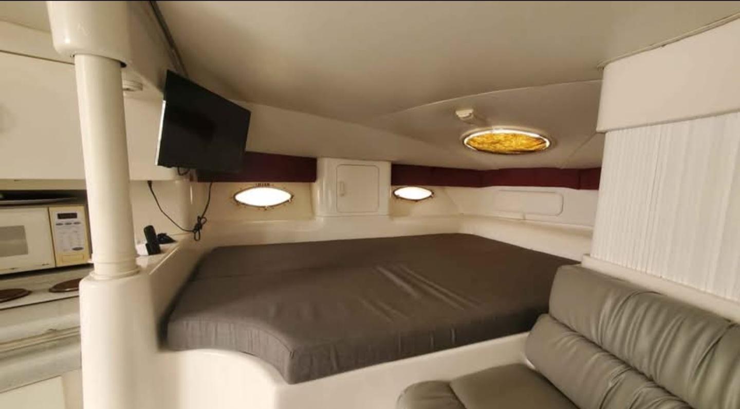 1997 Chris-Craft 34 interior cabin with bed, TV, and seating area.