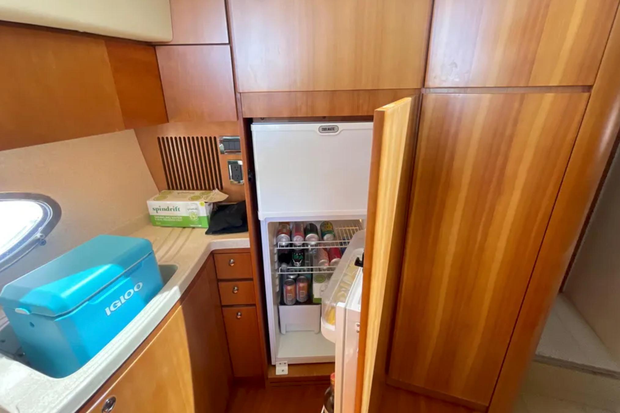2004 Azimut 46 yacht kitchen with open fridge, wooden cabinets, and countertop cooler.