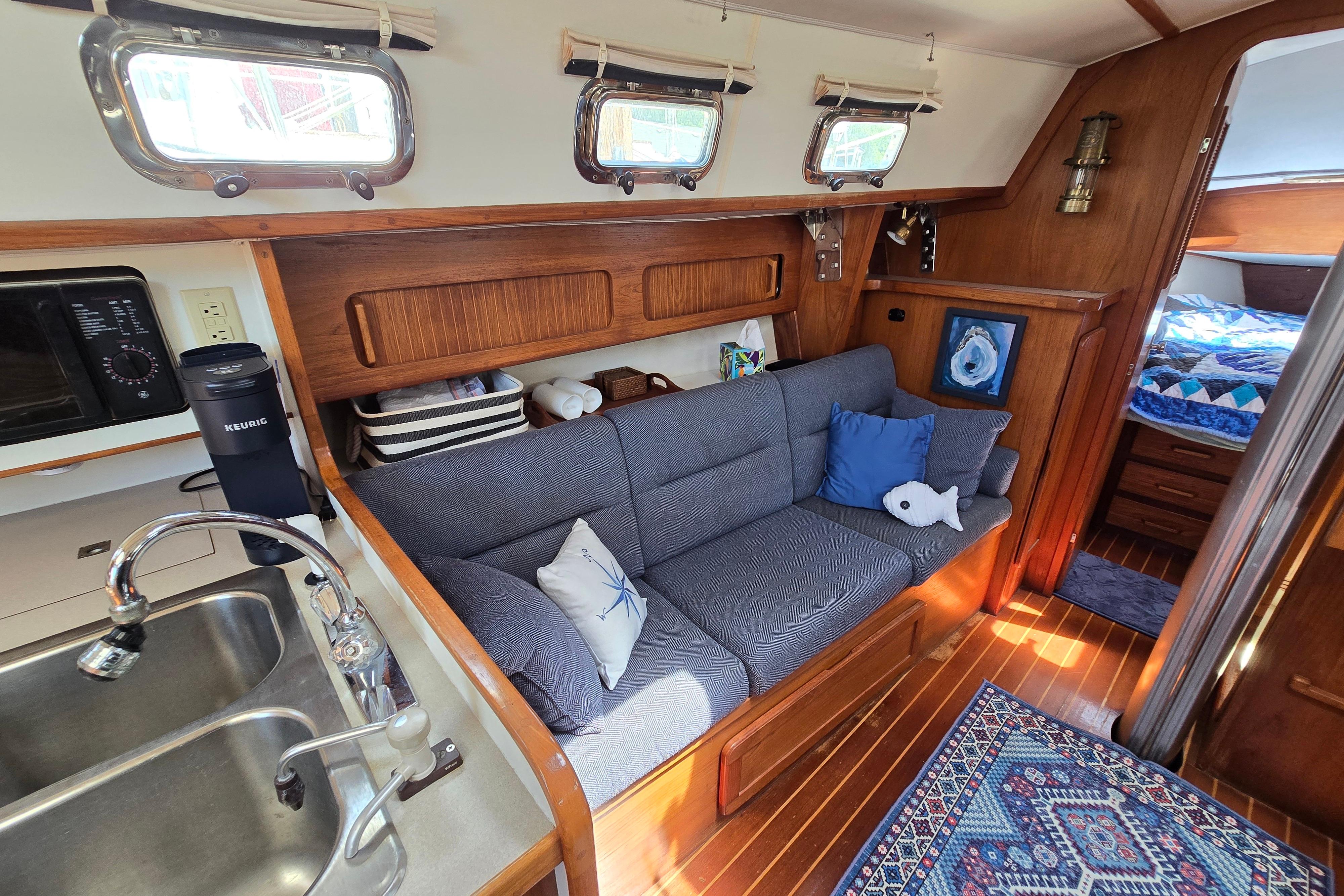 Cozy interior of a 1993 Caliber 35 sailboat with a sofa, kitchen, and nautical decor.