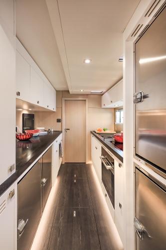 Modern galley kitchen in 2025 Privilege Signature 650 yacht, featuring sleek cabinetry and stainless steel appliances.