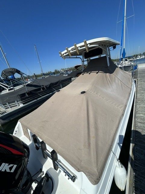 A 2000 Aquasport Osprey 250 boat docked, featuring a cover and outboard motor.