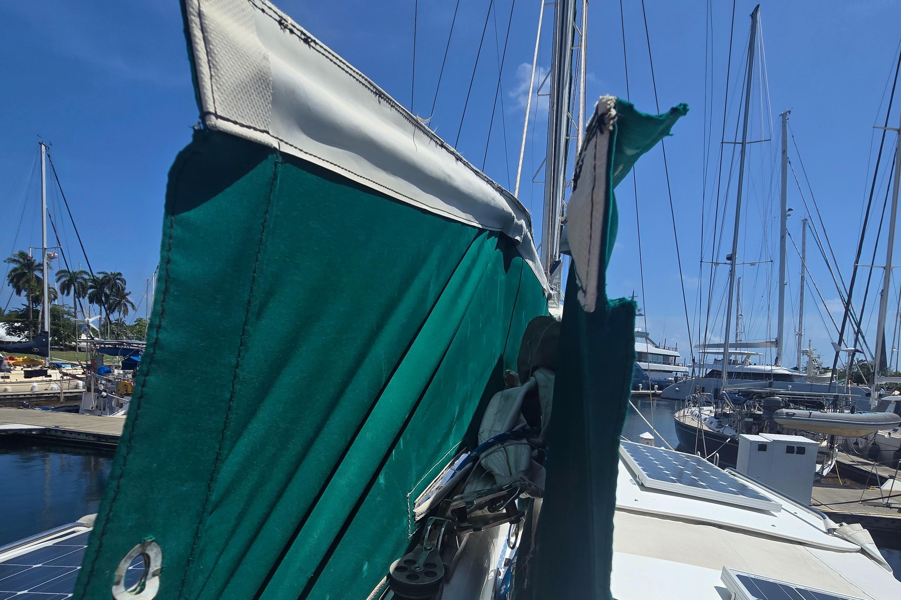Herreshoff 50 sailboat from 1978 with green canvas cover in a marina.