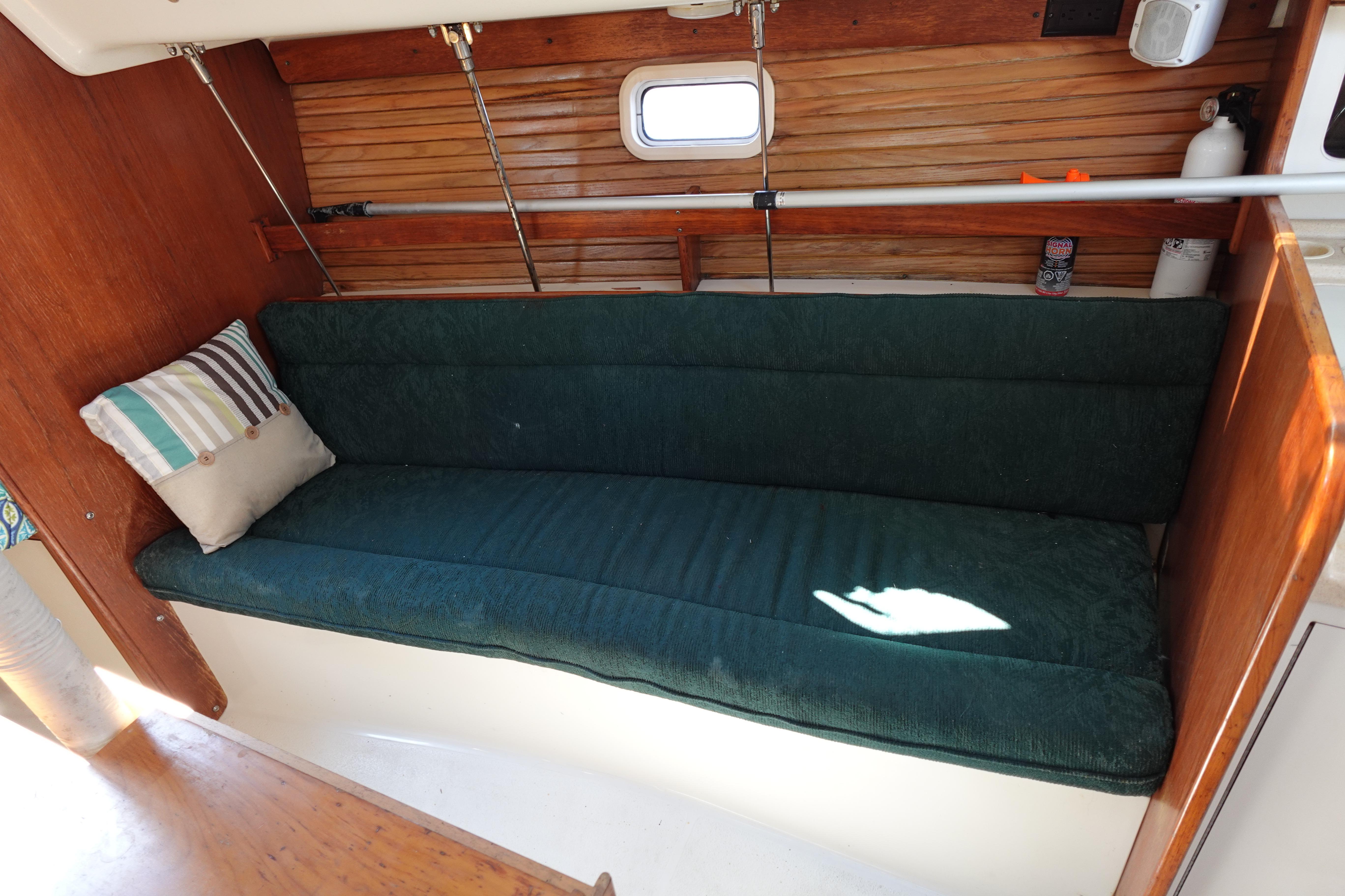 Interior of a 1997 Catalina 28 sailboat with green cushioned seating and wooden paneling.