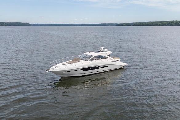 2016 Sea Ray Sundancer 510 yacht cruising on a calm lake under a clear sky.