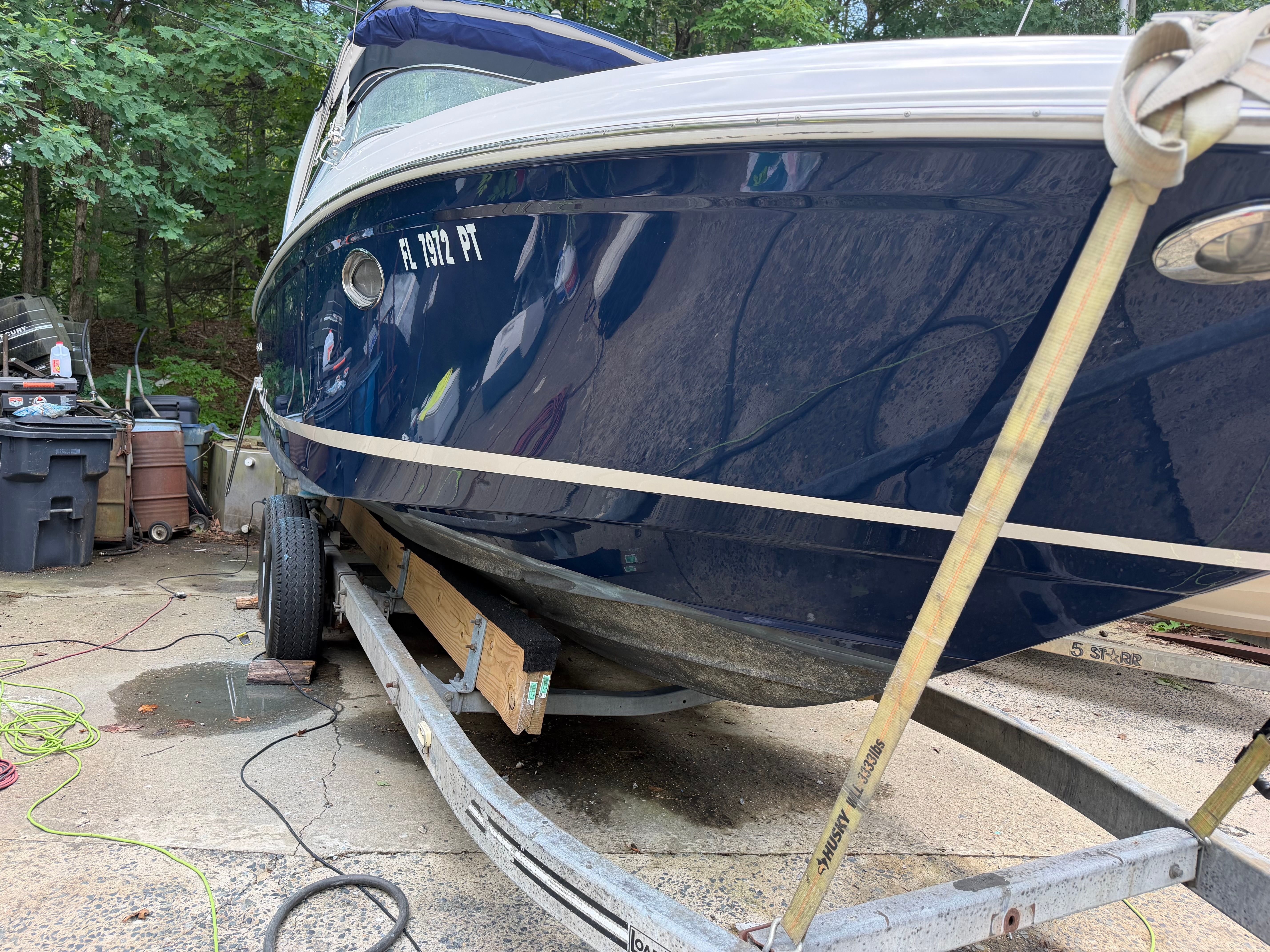 A 2011 Regal 2750 Cuddy boat on a trailer, surrounded by trees and equipment.