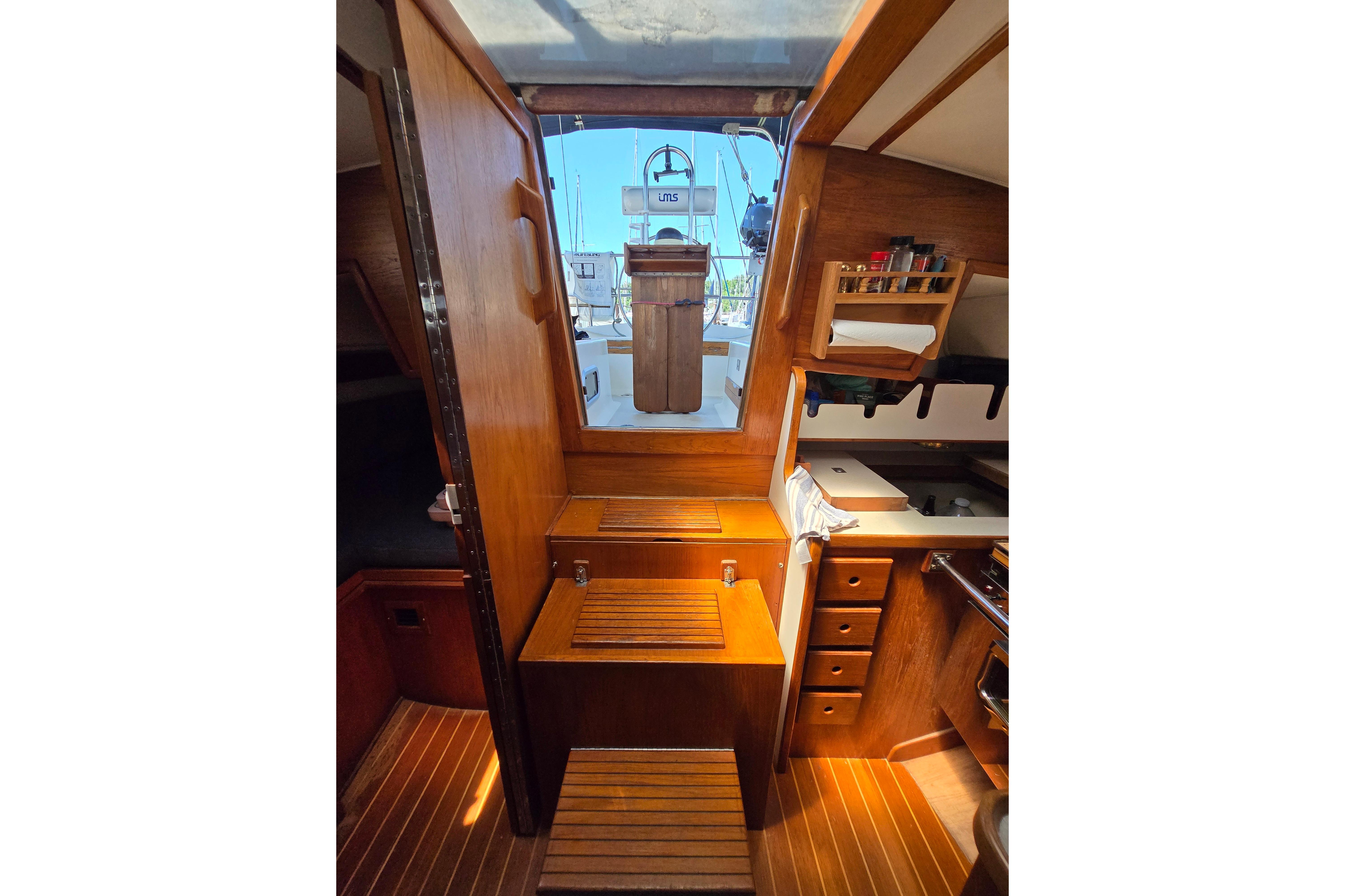 Interior of 1993 Caliber 35 sailboat, featuring wooden cabinetry and compact kitchen area.