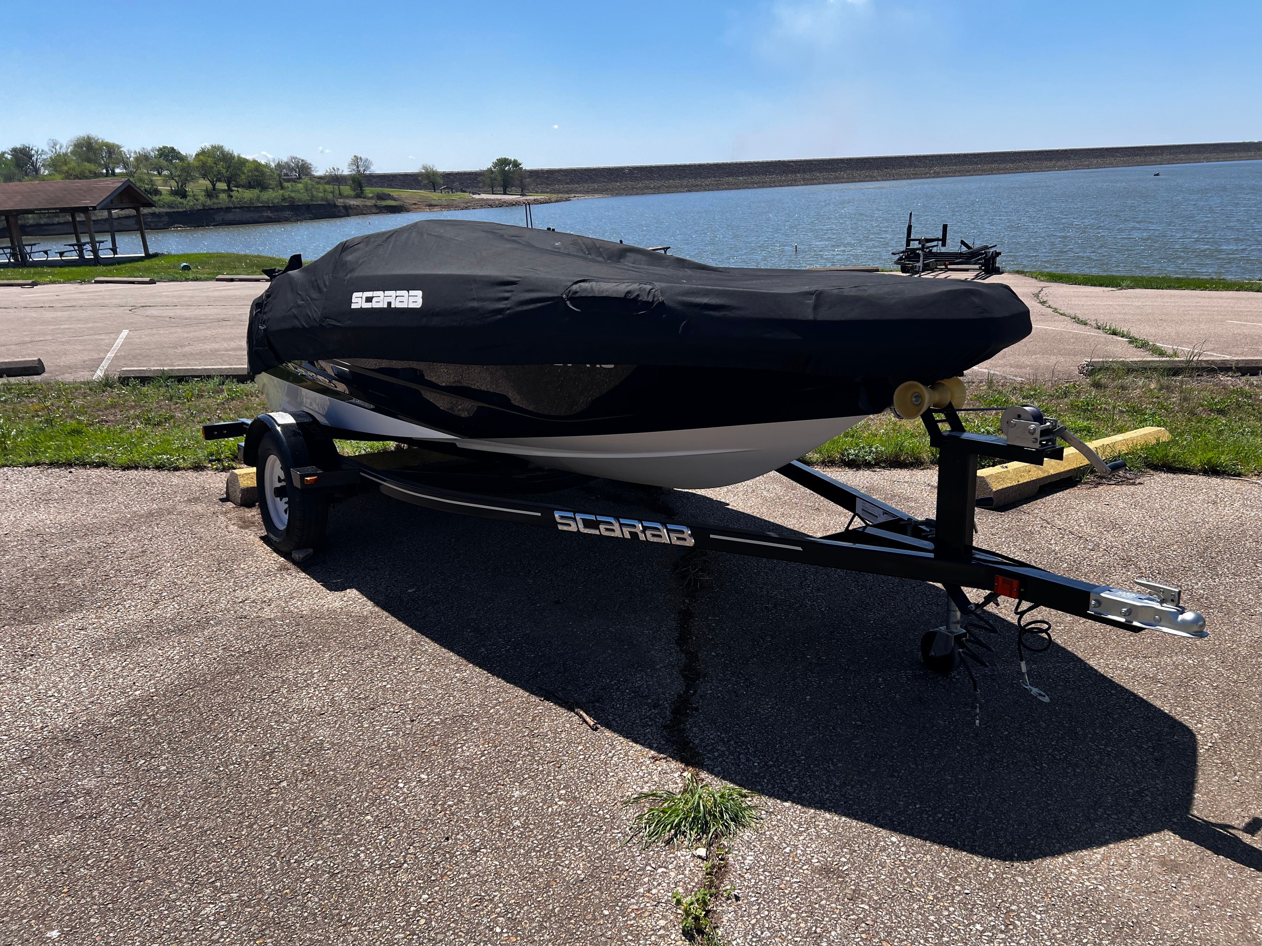 A 2019 Scarab 165 G boat is on a trailer in a parking area.