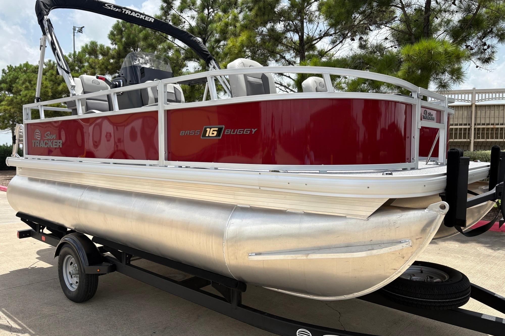 2026 Sun Tracker Bass Buggy 16 XL Select pontoon boat on trailer, red and silver design.