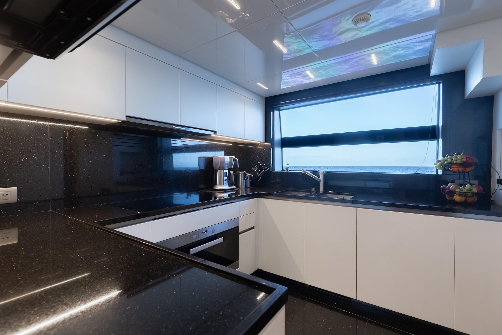 Modern kitchen interior on 2020 Sanlorenzo SLA120A yacht, featuring sleek black countertops and ocean view.