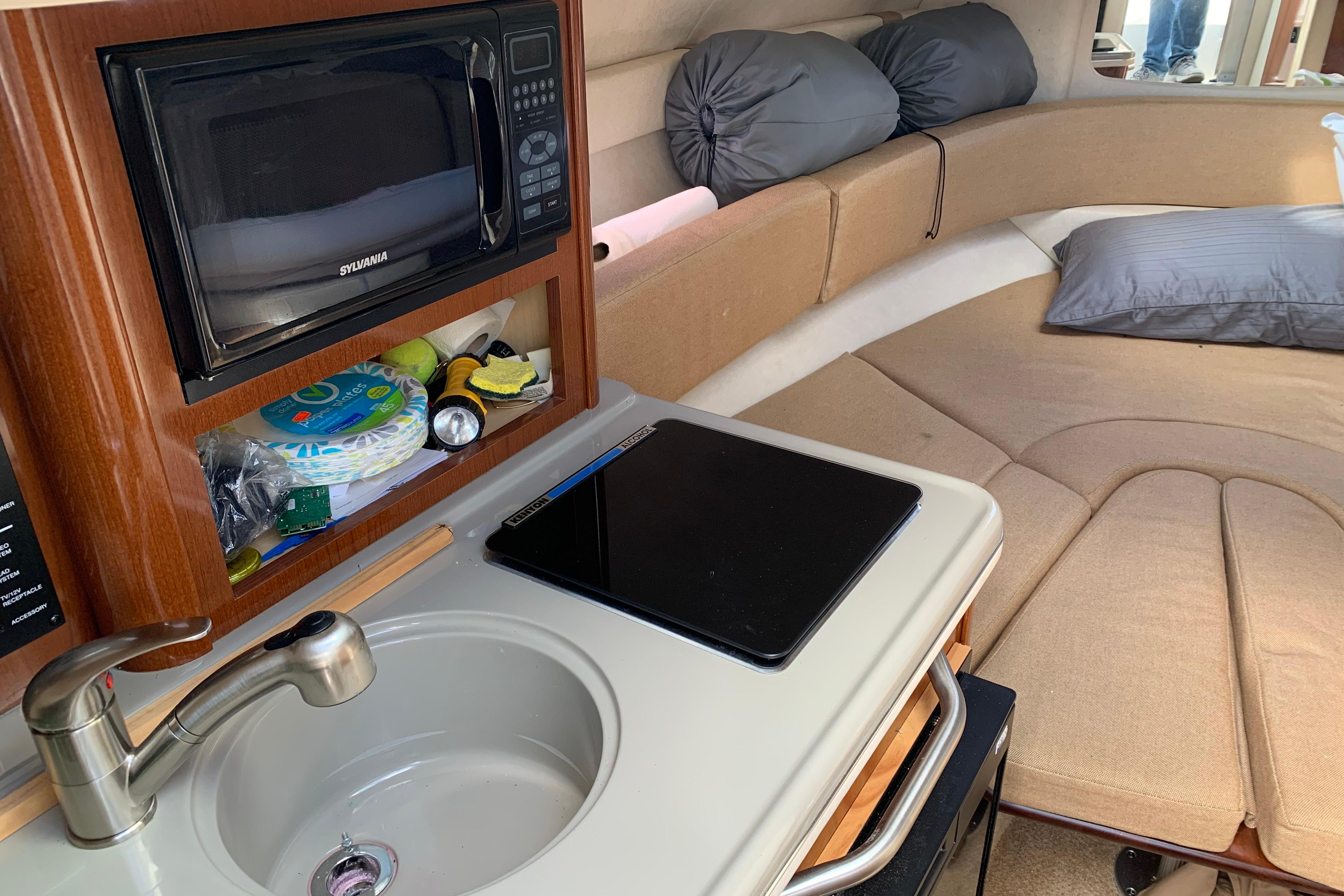 Interior of 2012 Sea Ray 240 Sundancer with kitchenette and cozy seating area.