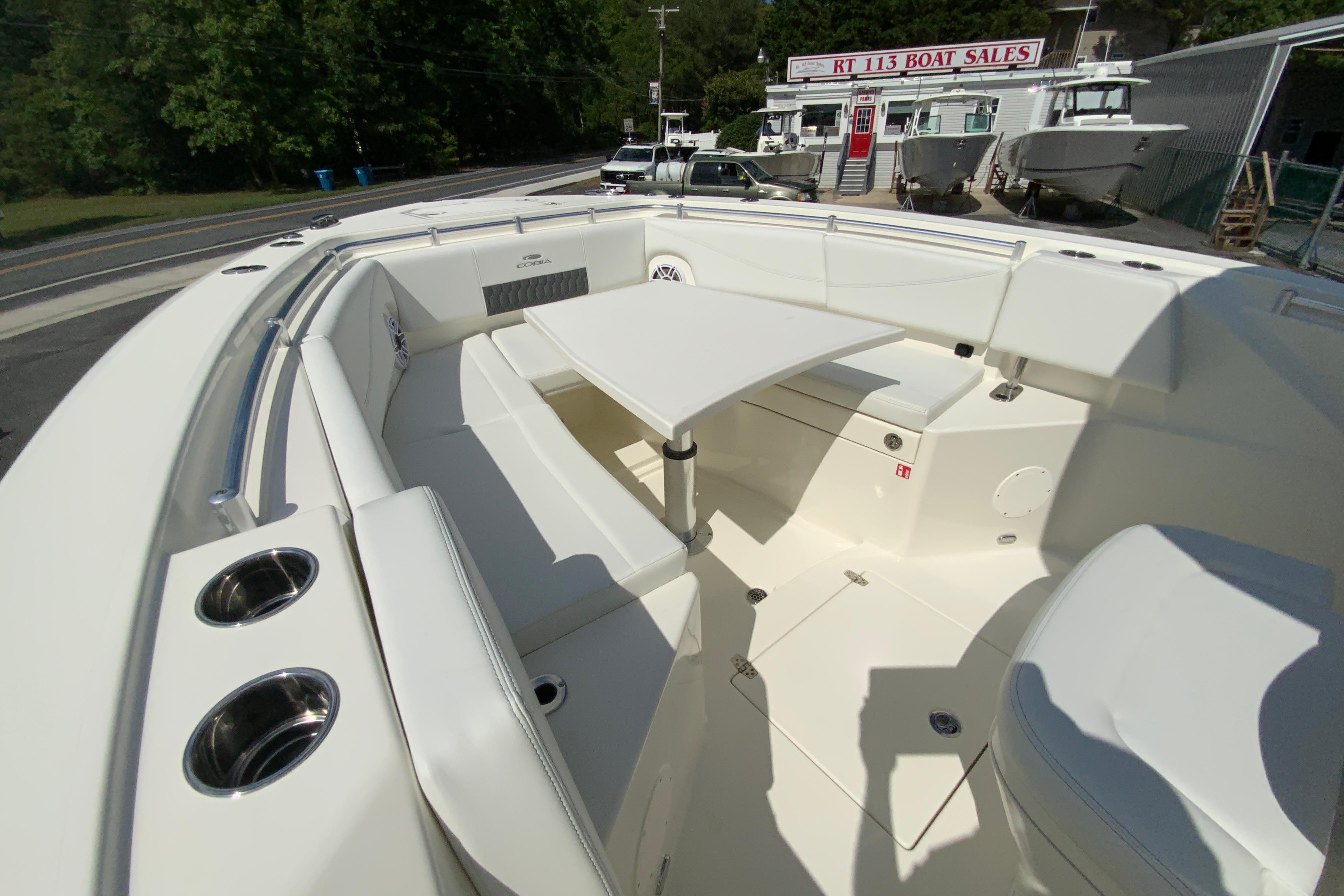 2027 Cobia 320 Center Console boat interior with seating and table, at a boat sales location.