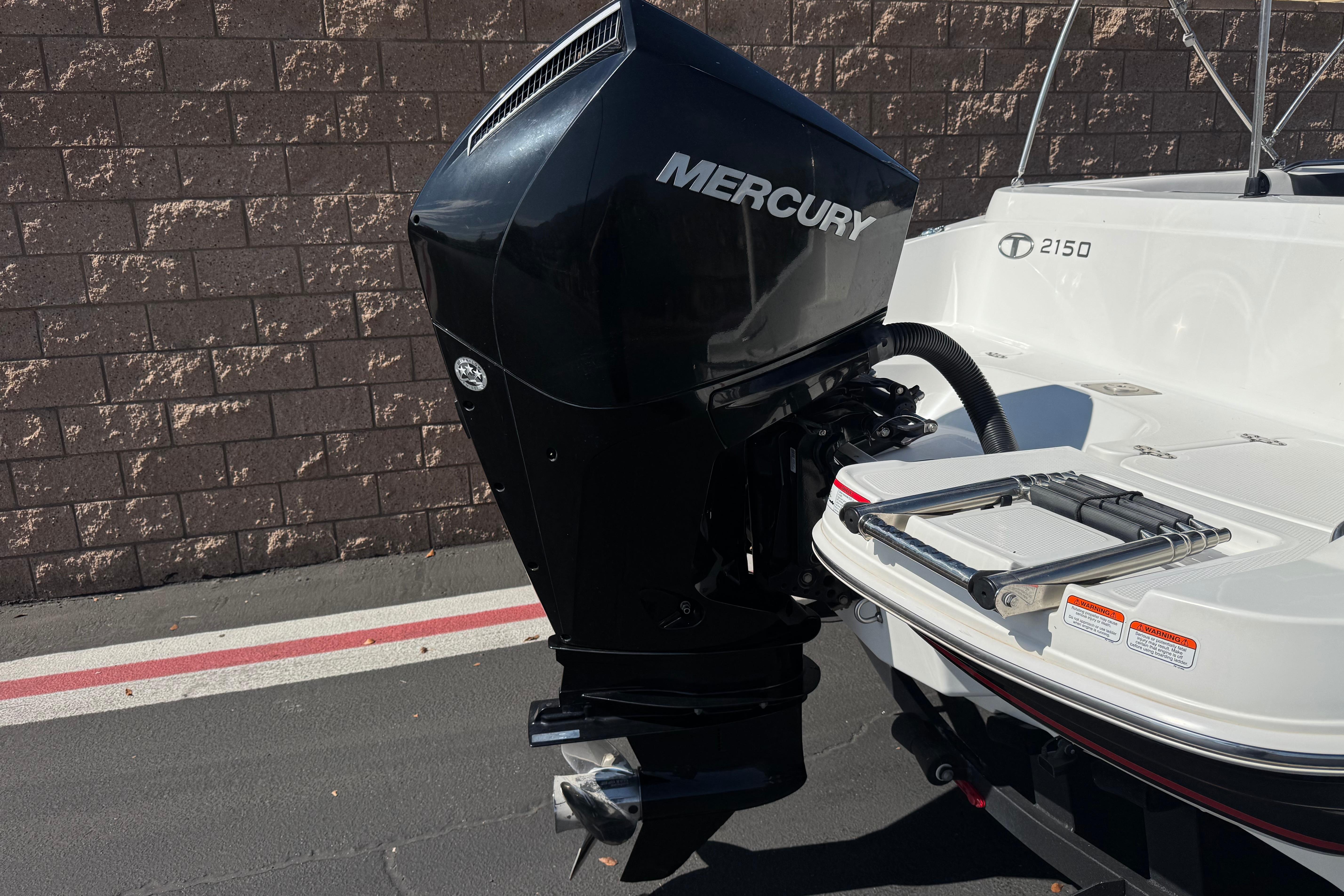 2019 Tahoe 2150 boat with Mercury outboard motor, parked on pavement.
