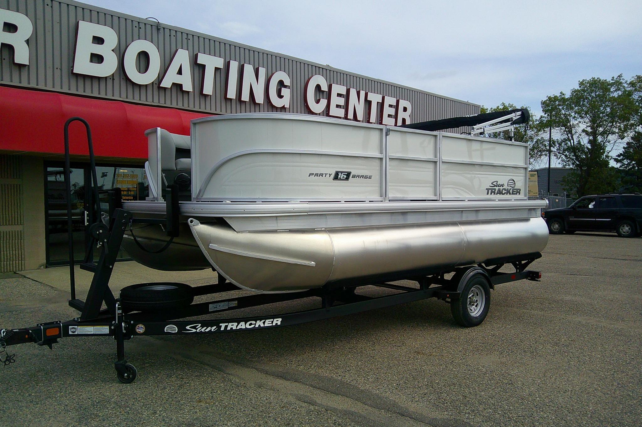 2026 Sun Tracker Party Barge 16 DLX pontoon boat on trailer outside boating center.