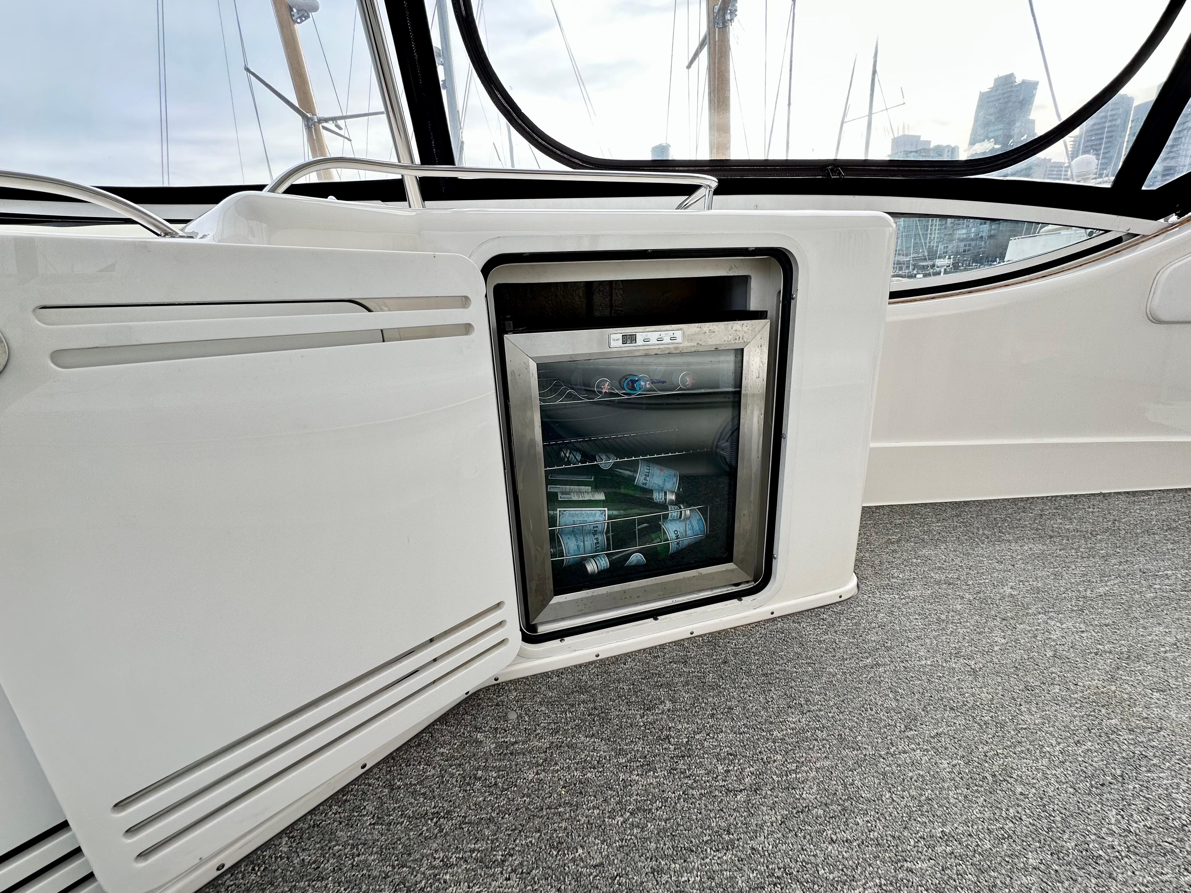 2002 Sea Ray 560 Sedan Bridge interior with mini fridge and open cabinet.
