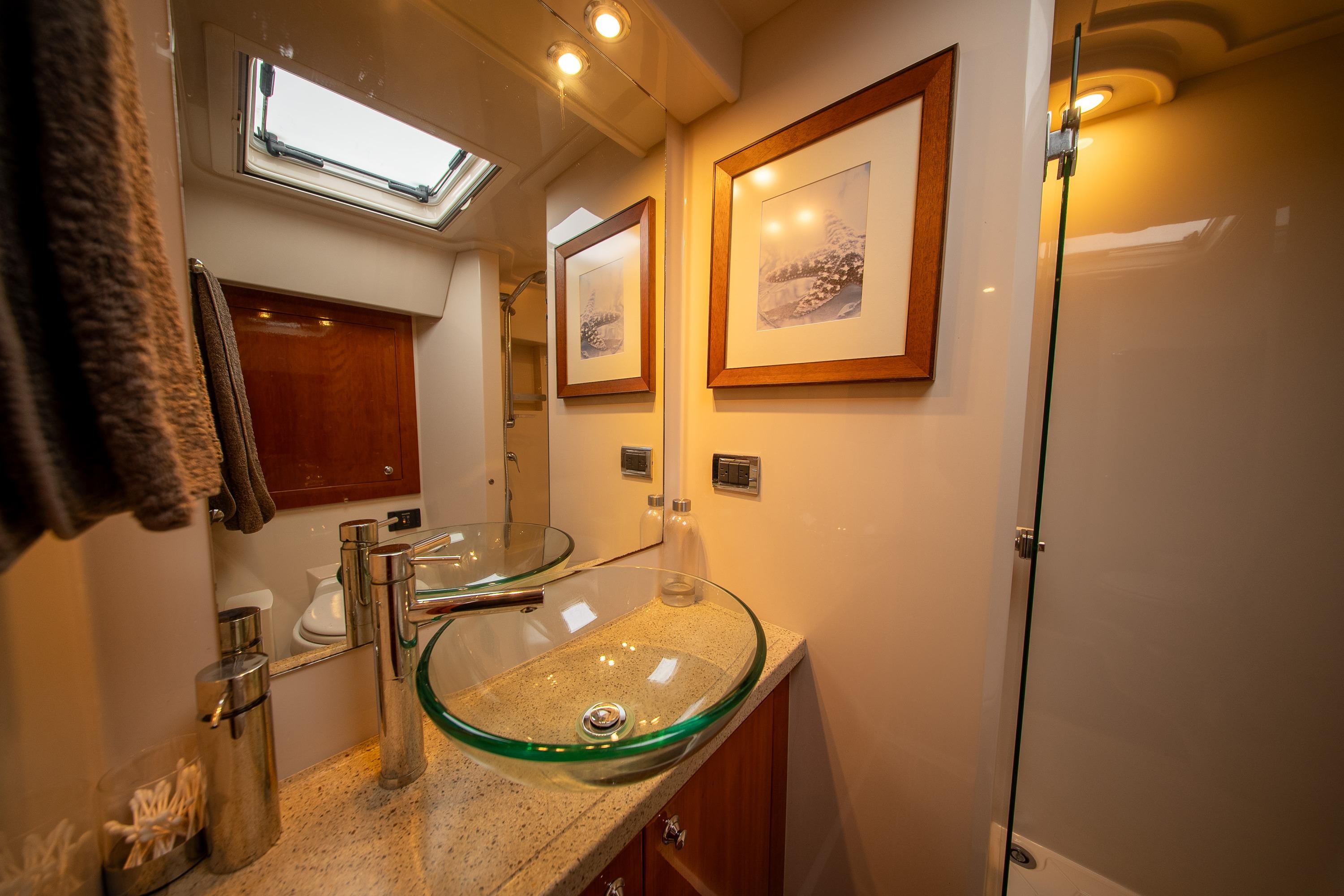 Luxurious bathroom in 2011 Riviera 5000 Sport Yacht with glass sink and elegant decor.