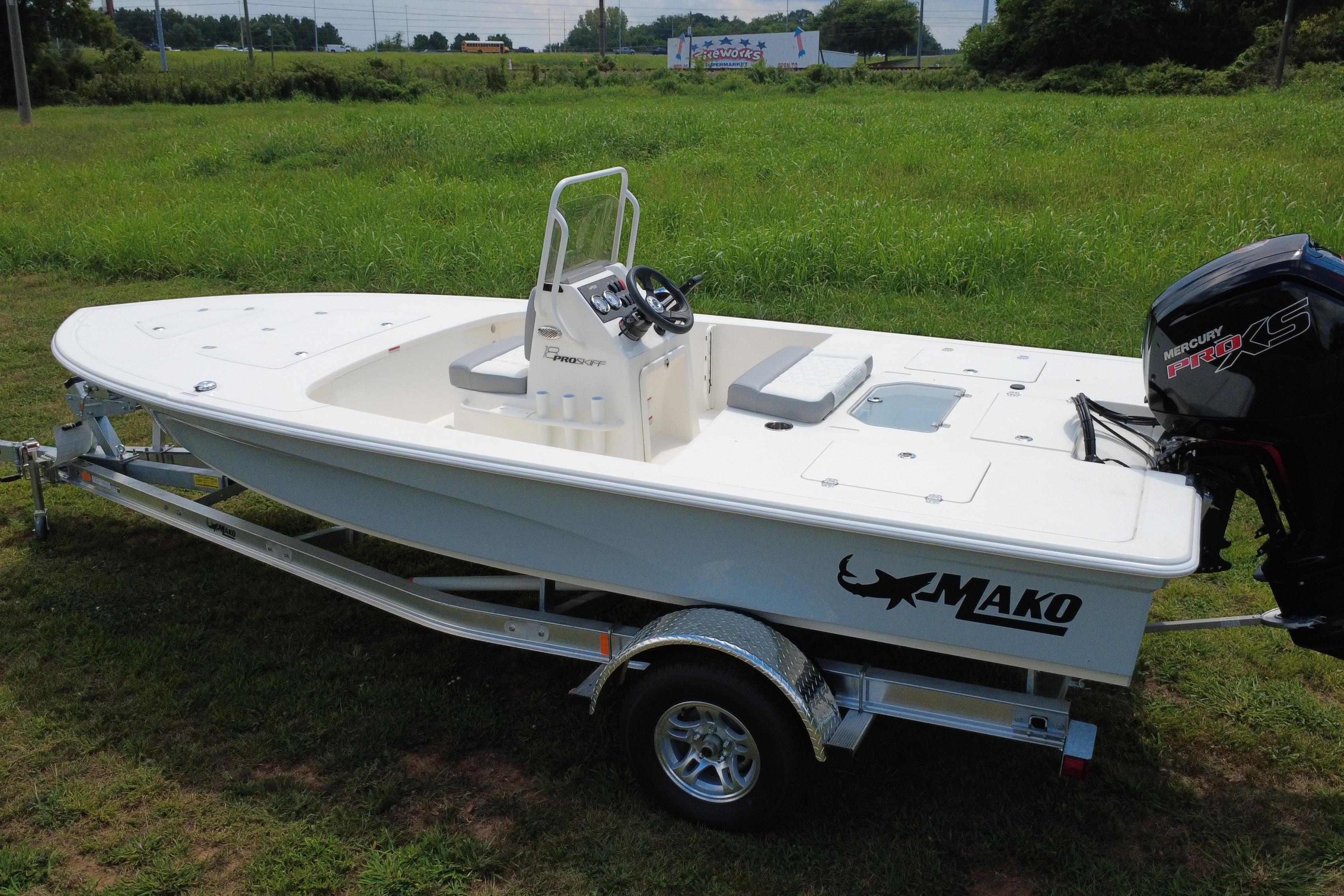 2026 Mako 18 Pro Skiff boat on trailer, parked on grassy field.