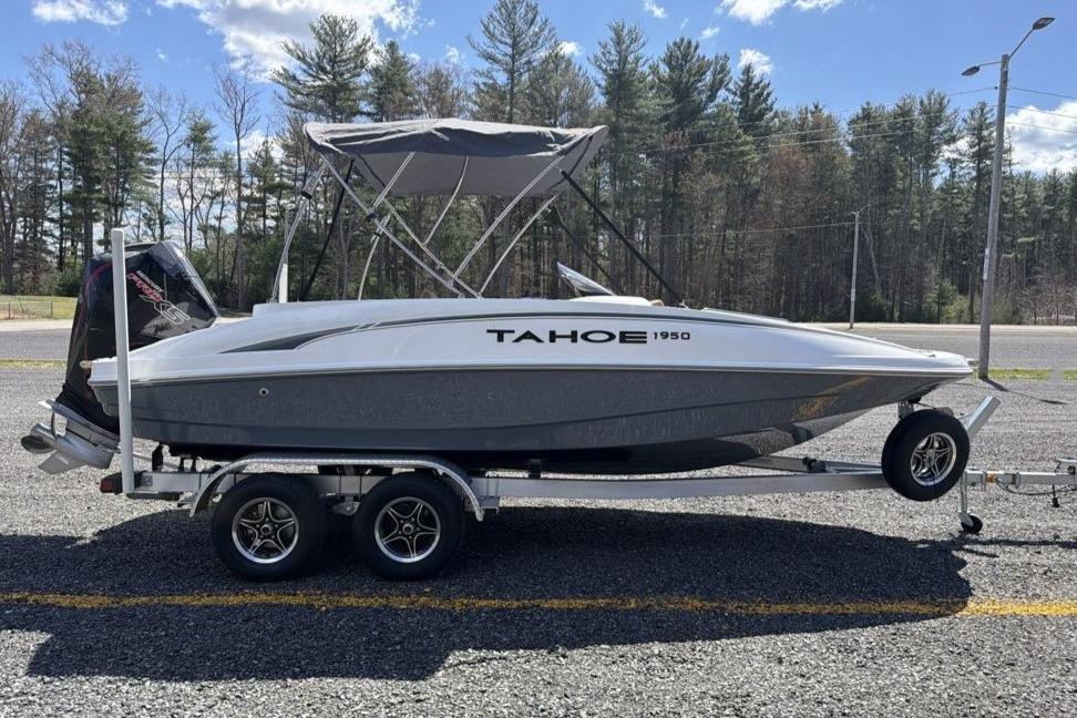 2026 Tahoe 1950 boat on trailer, parked outdoors with trees in background.
