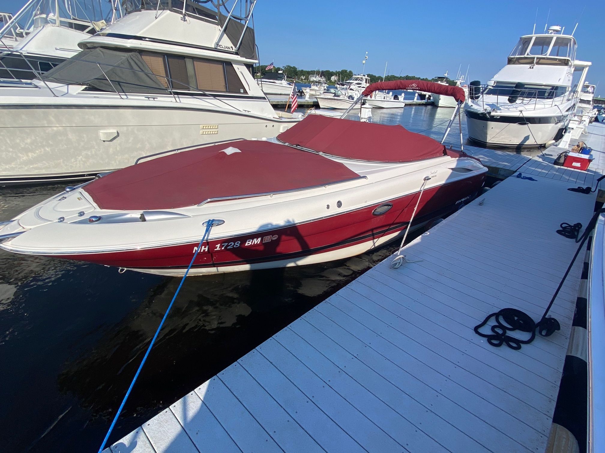 A 2006 Monterey 268SS Super Sport docked. It features a red cover and is surrounded by other boats.