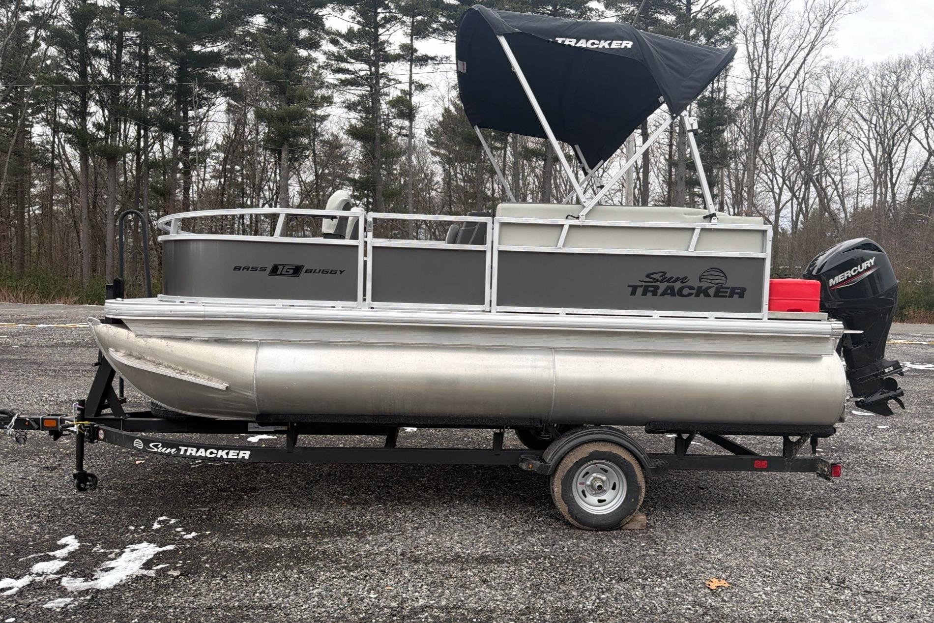 2026 Sun Tracker Bass Buggy 16 XL Select pontoon boat on trailer, parked outdoors.