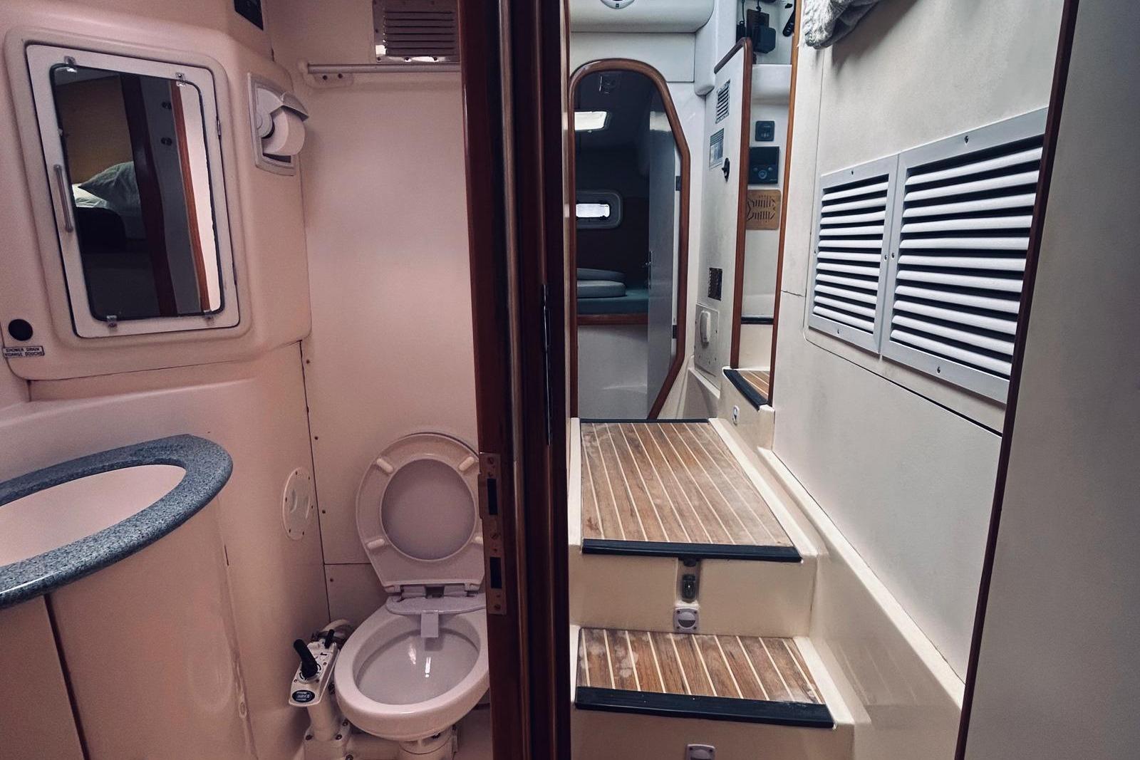 Interior of a 2001 Robertson & Caine Leopard yacht, featuring a compact bathroom and wooden steps.