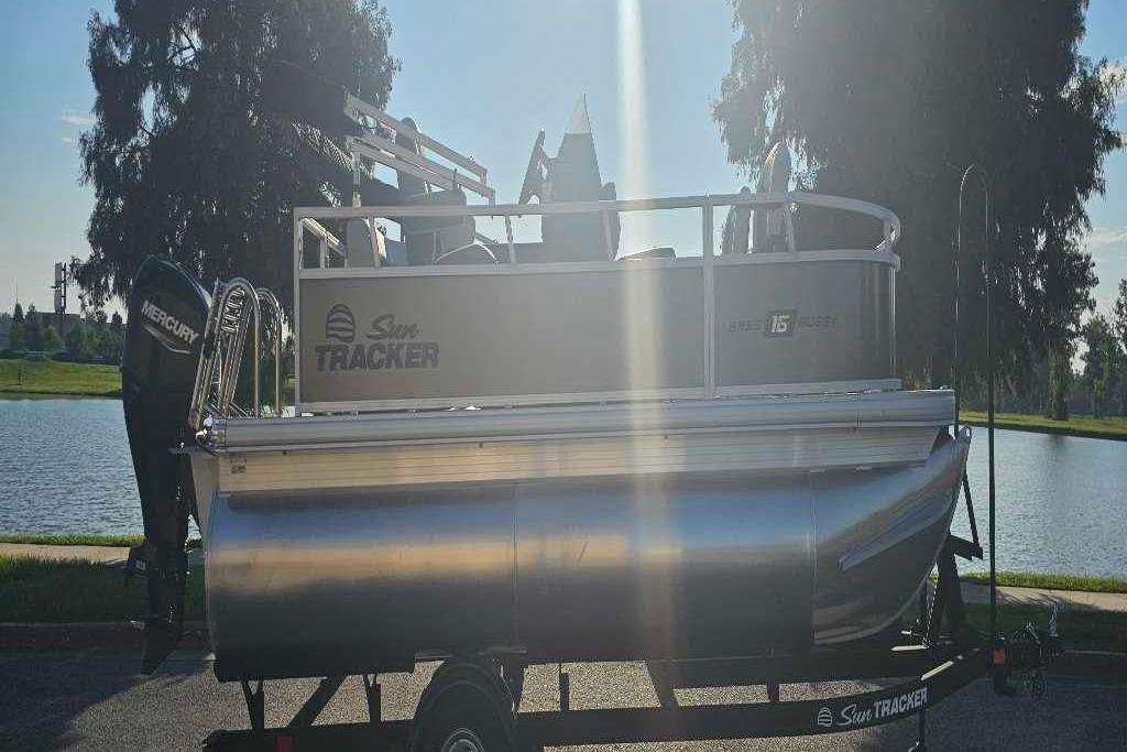 2026 Sun Tracker Bass Buggy 16 XL Select pontoon boat by a lake.