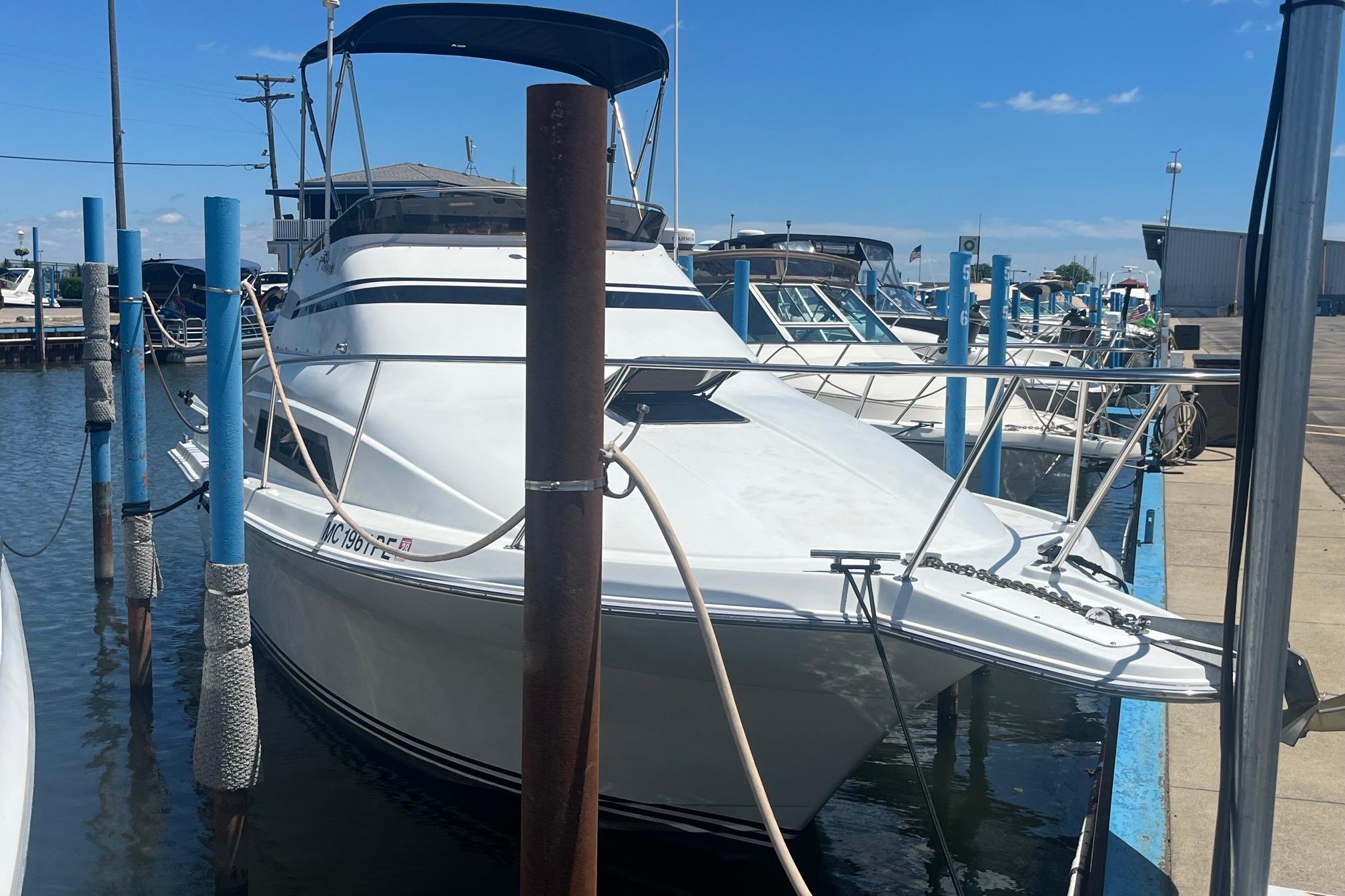 1988 Seafox 29 Flybridge boat docked at marina under clear blue sky.
