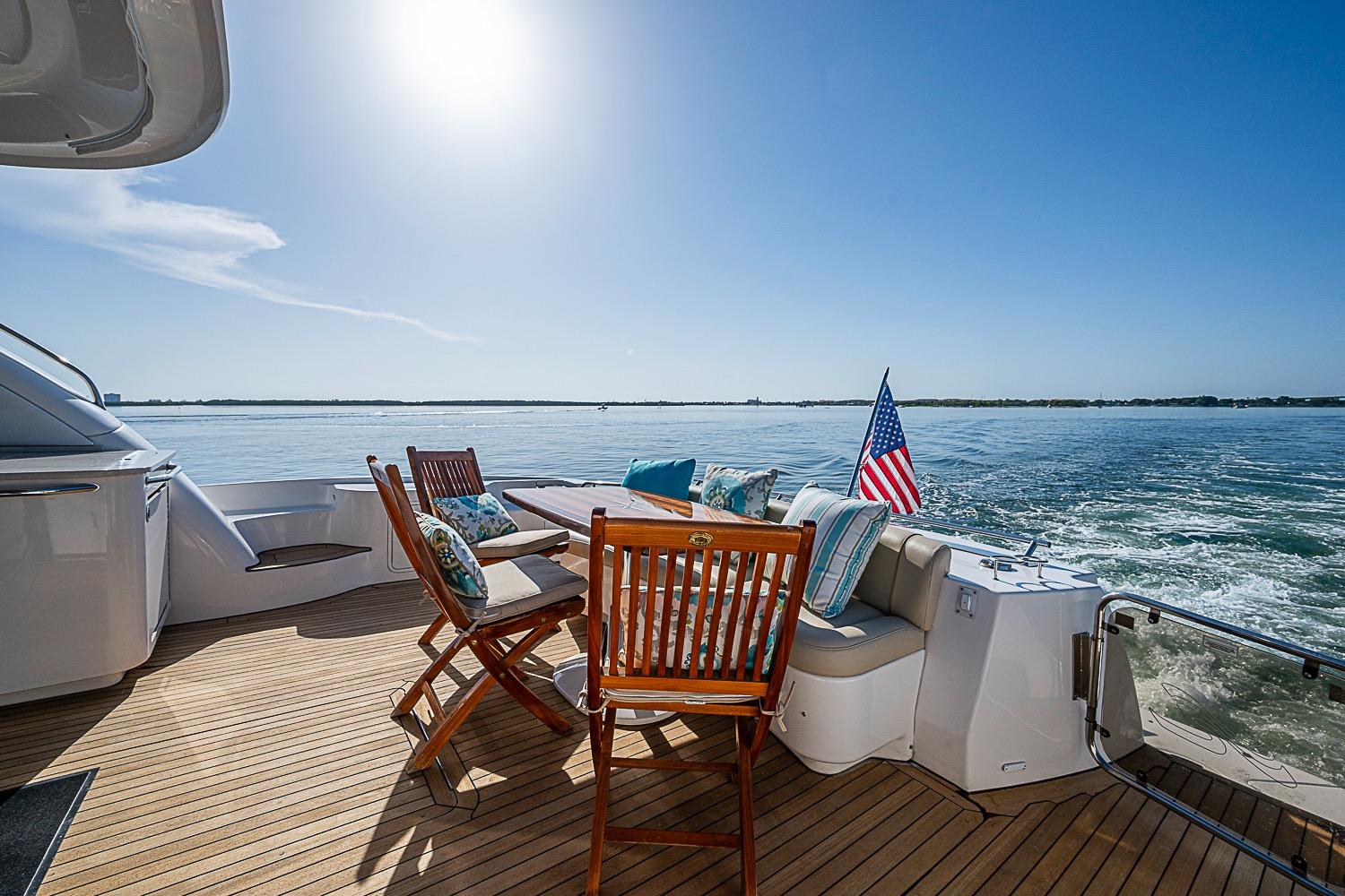 2008 Sea Ray 60 Sundancer yacht deck with chairs, table, and American flag on open water.