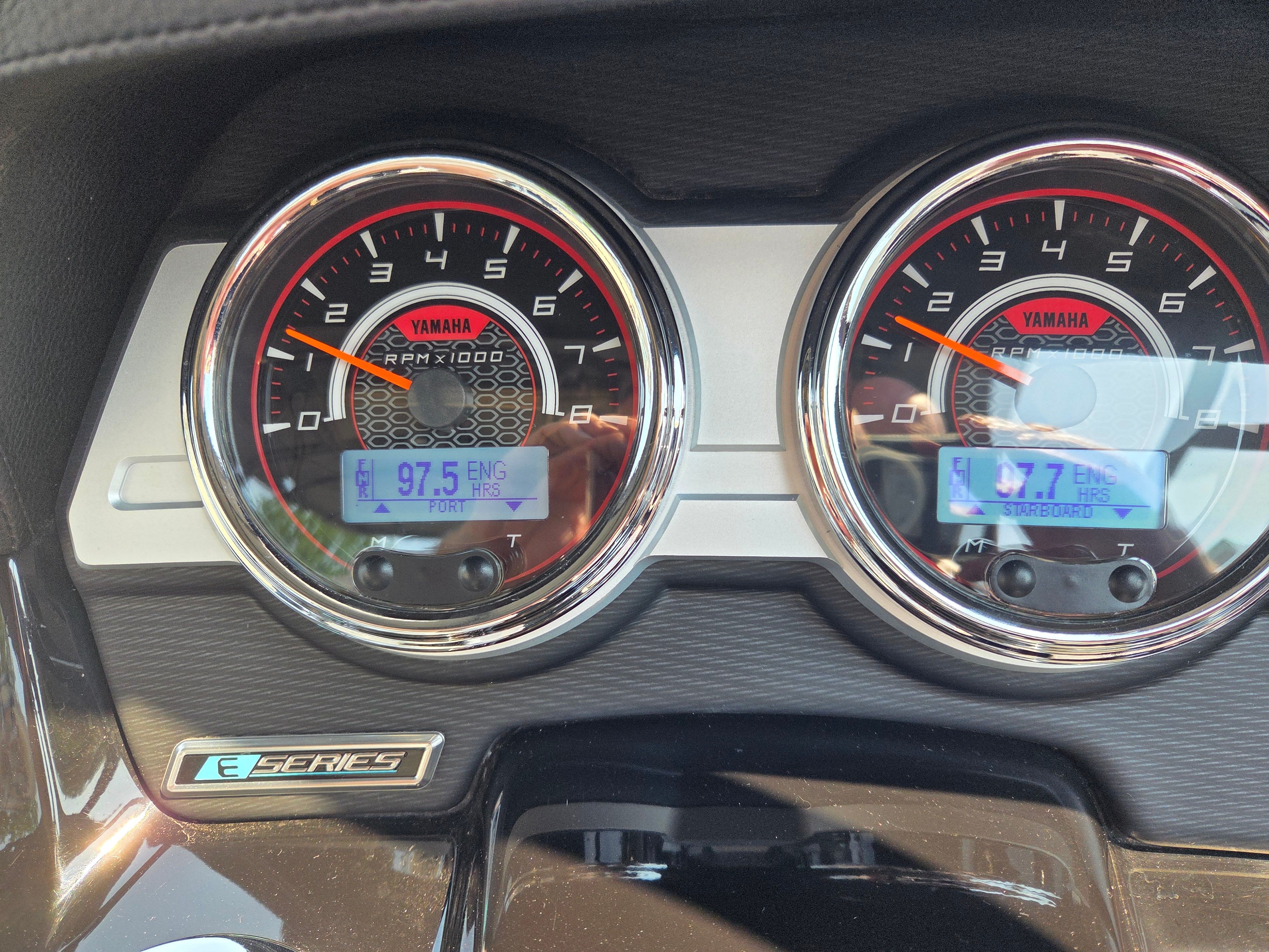 Close-up of a Yamaha 242X E-Series boat dashboard with two round gauges.