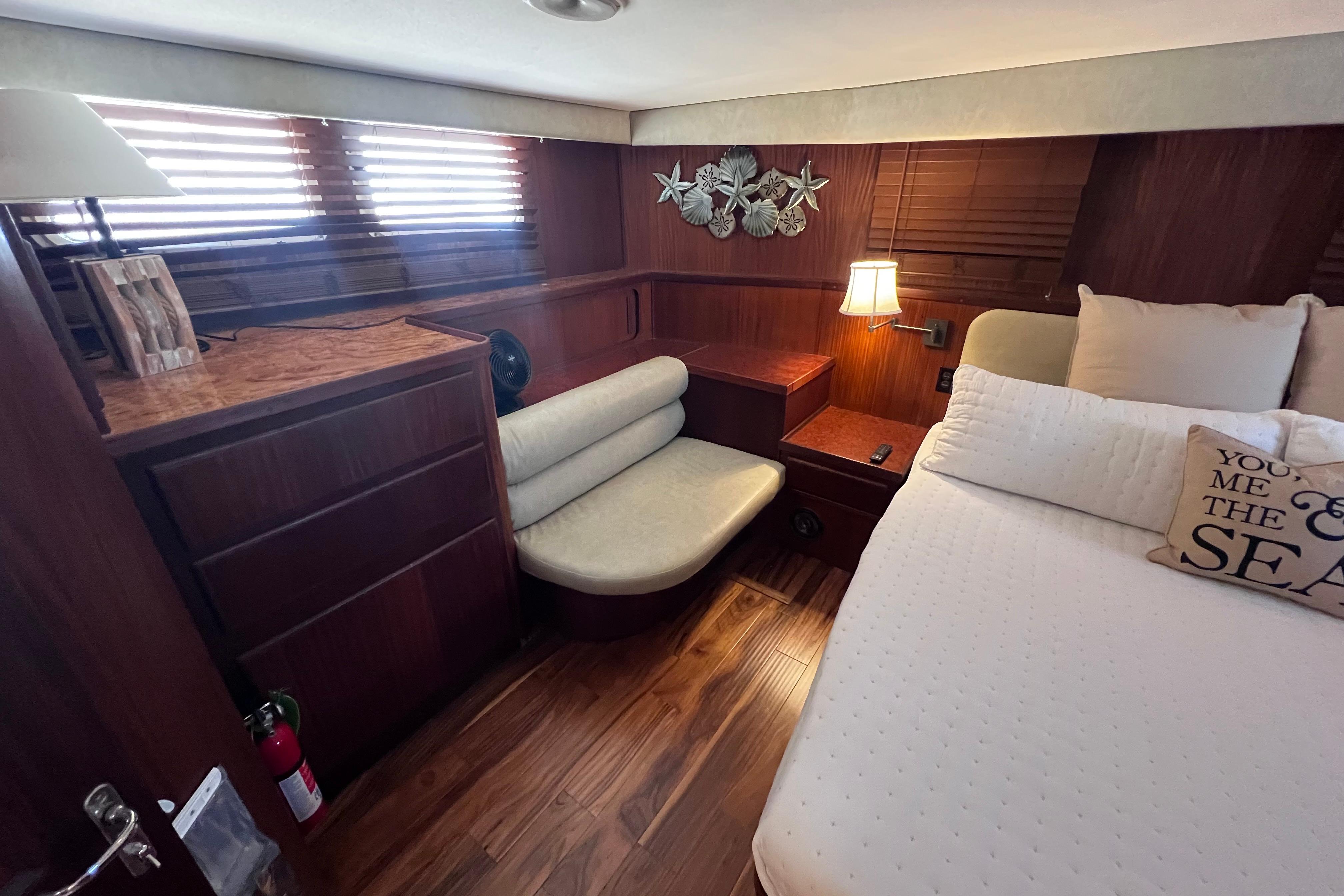 Cozy bedroom in 1987 Hatteras 70 Cockpit Motor Yacht with wood accents and nautical decor.