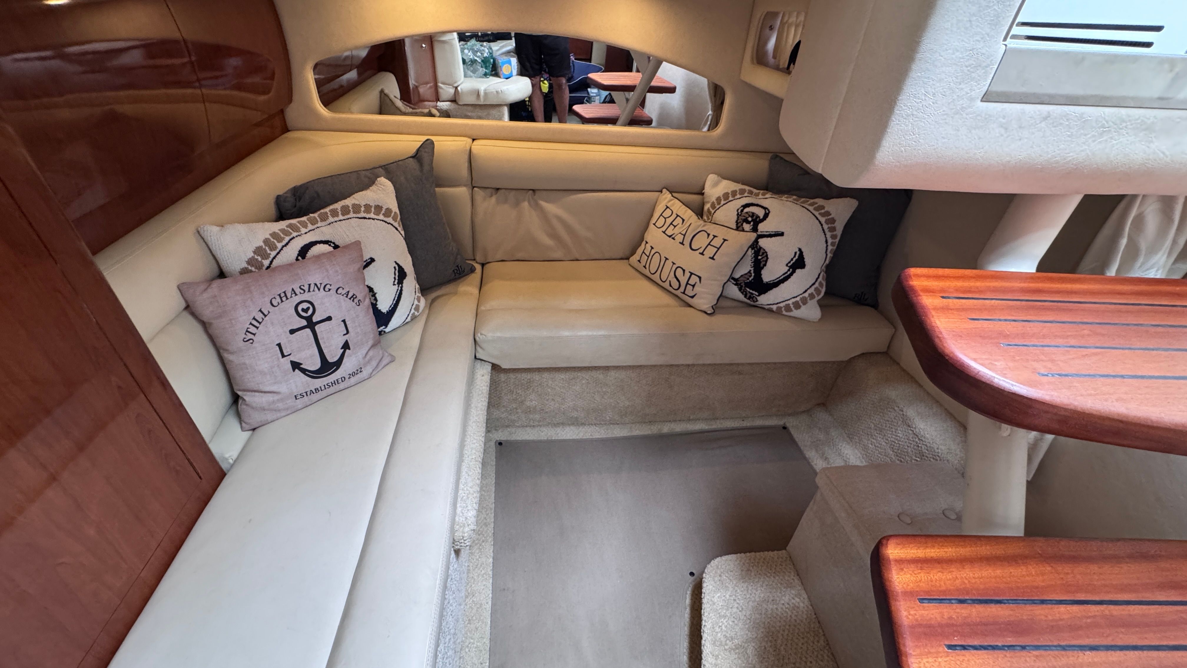 Interior of the 2003 Sea Ray 360 Sundancer with beige upholstery and nautical-themed pillows.